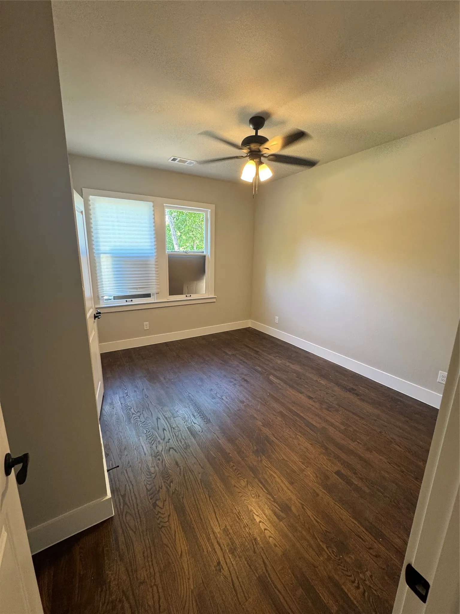 Spare room with dark wood-style floors, ceiling fan, and a textured ceiling