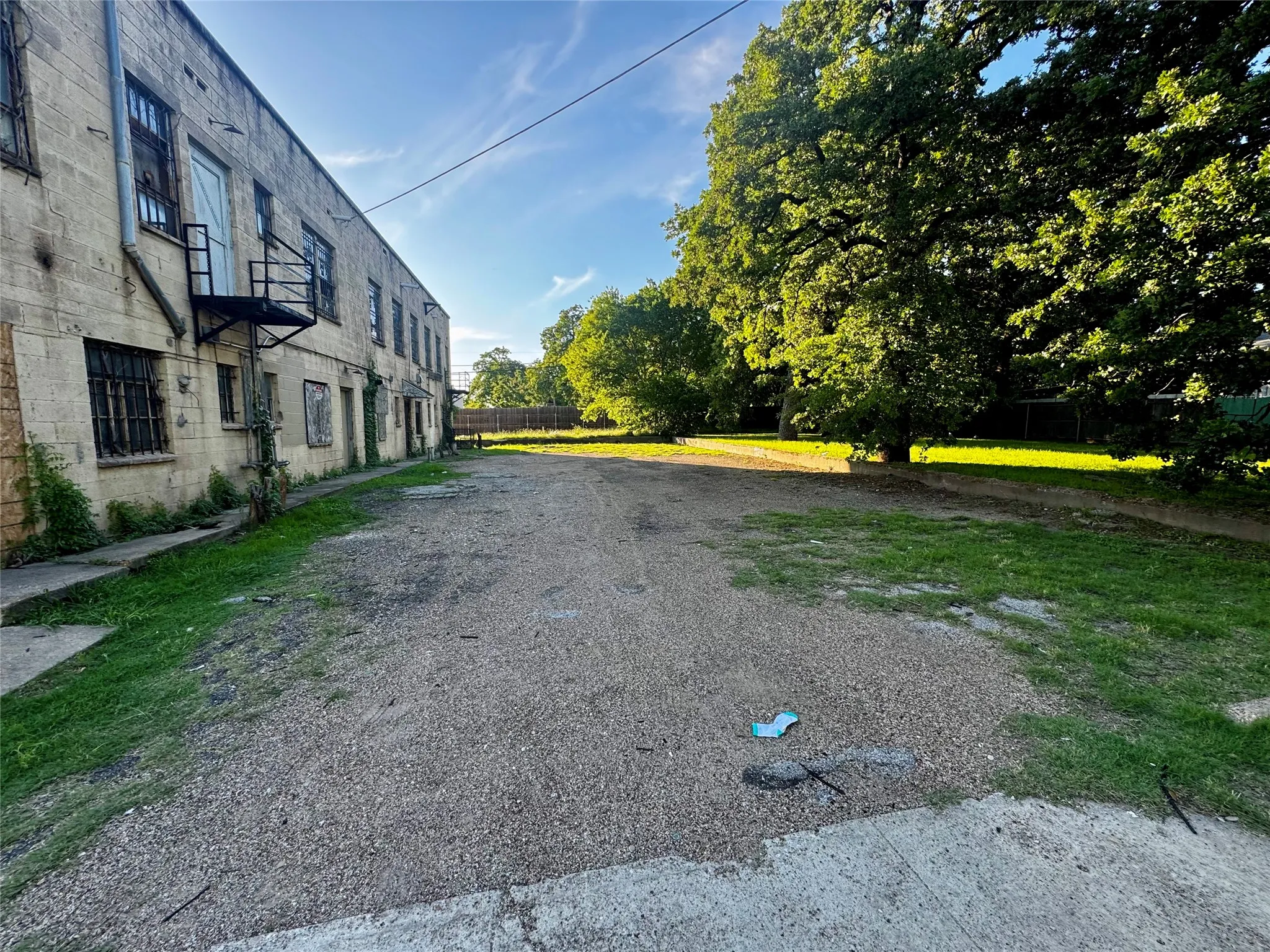Expansive gravel rear parking lot backing to vacant residential lot