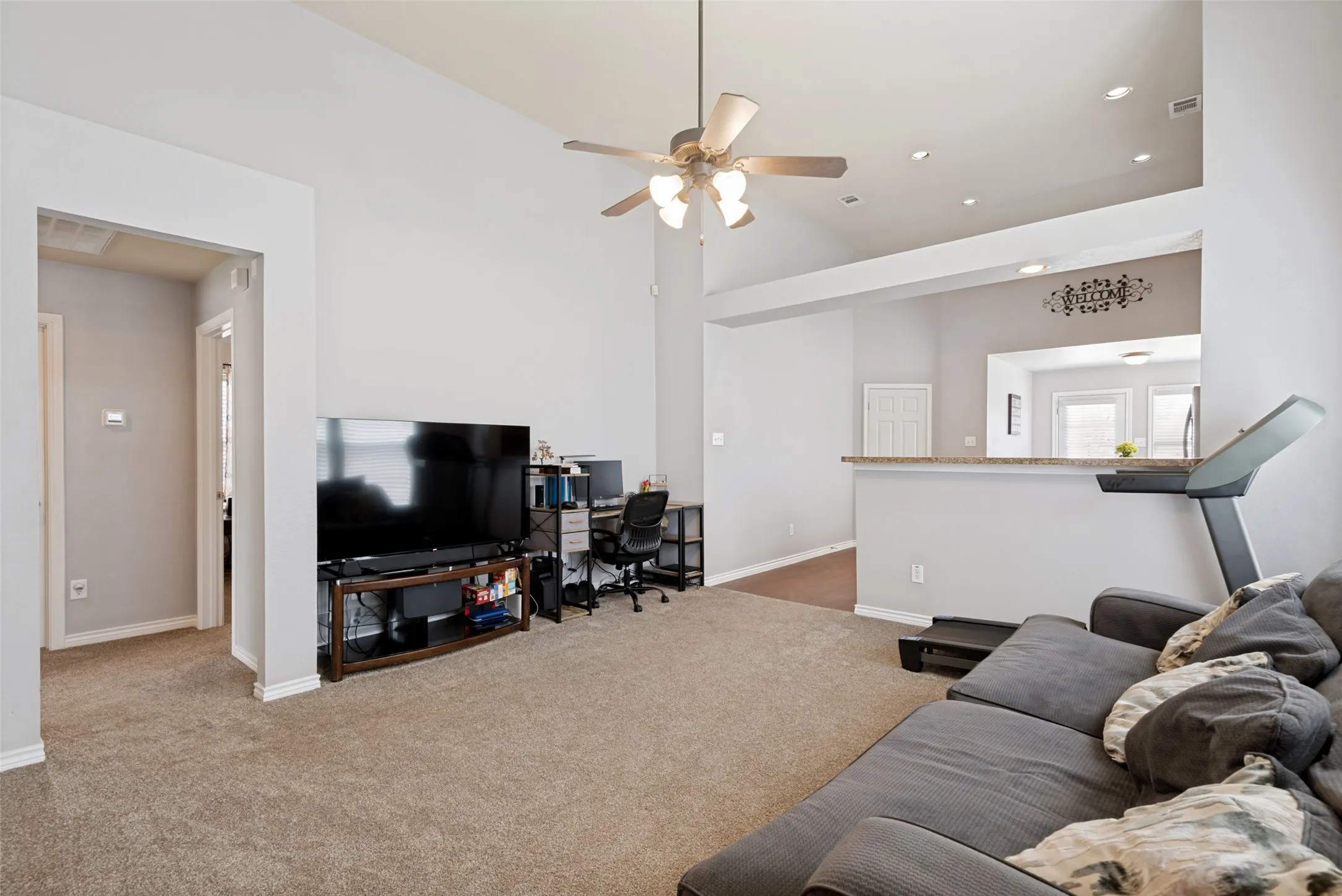 Spacious living area featuring vaulted ceilings, recessed lighting, and a ceiling fan