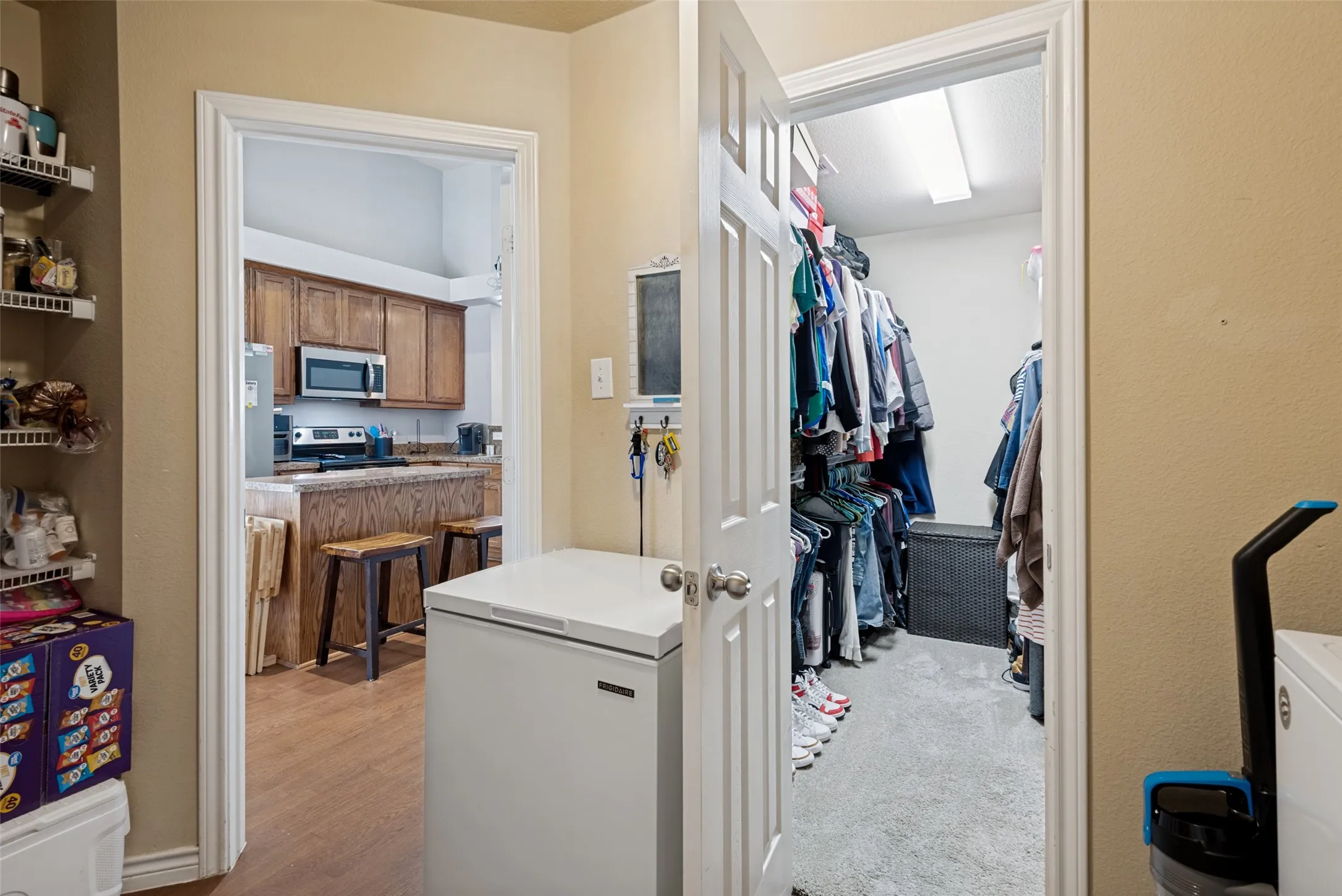 Laundry area featuring a chest freezer and access to a walk-in closet with carpet flooring