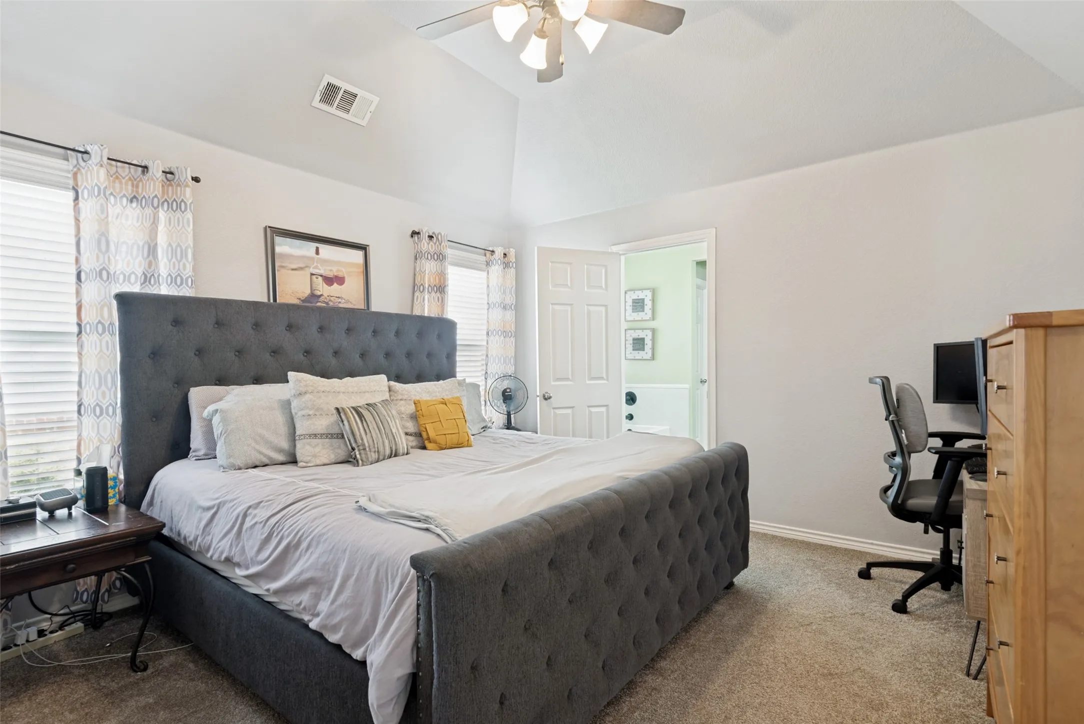 Carpeted room with vaulted ceilings and a ceiling fan