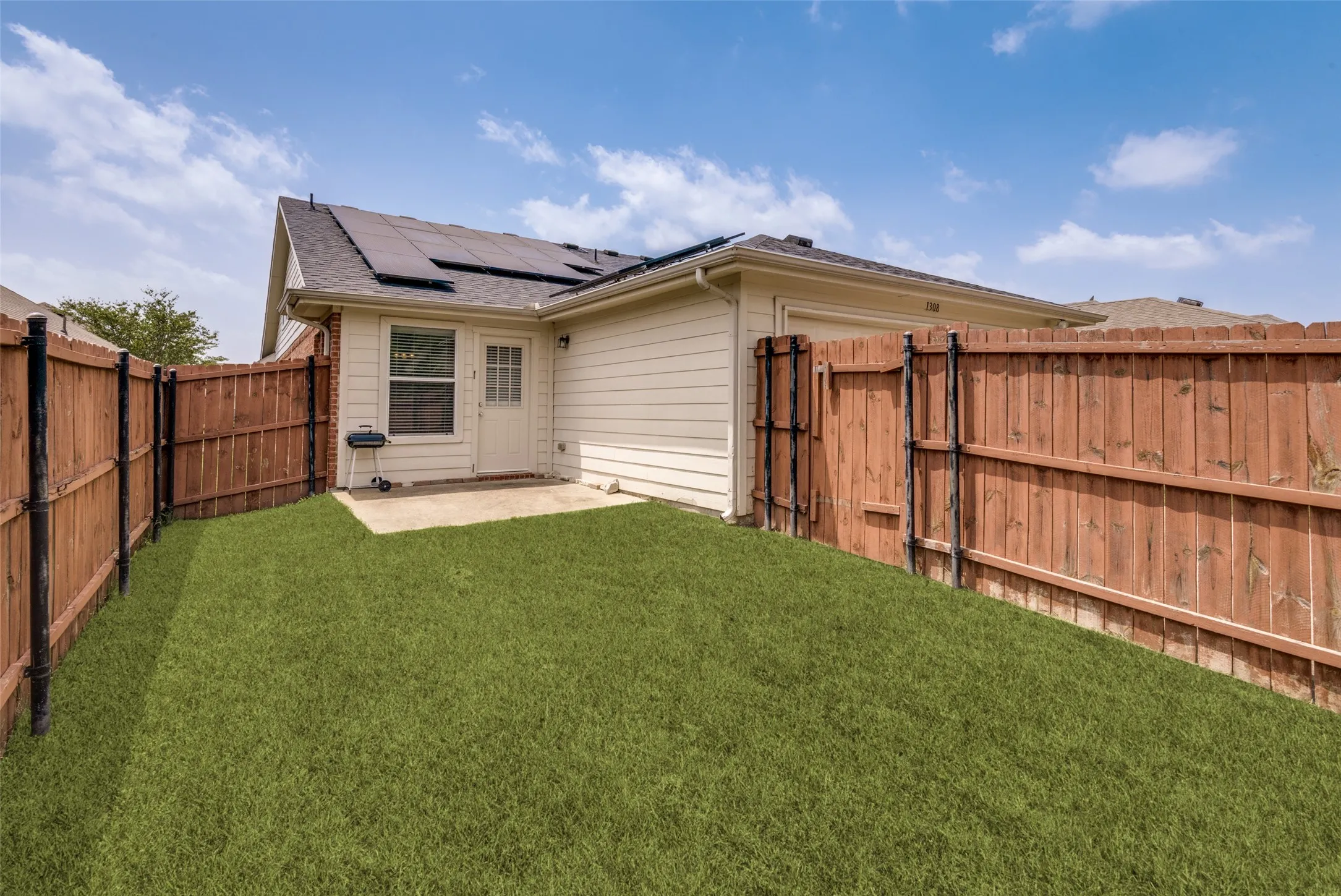 Private backyard featuring a concrete patio, perimeter wood fencing, and a grassy area