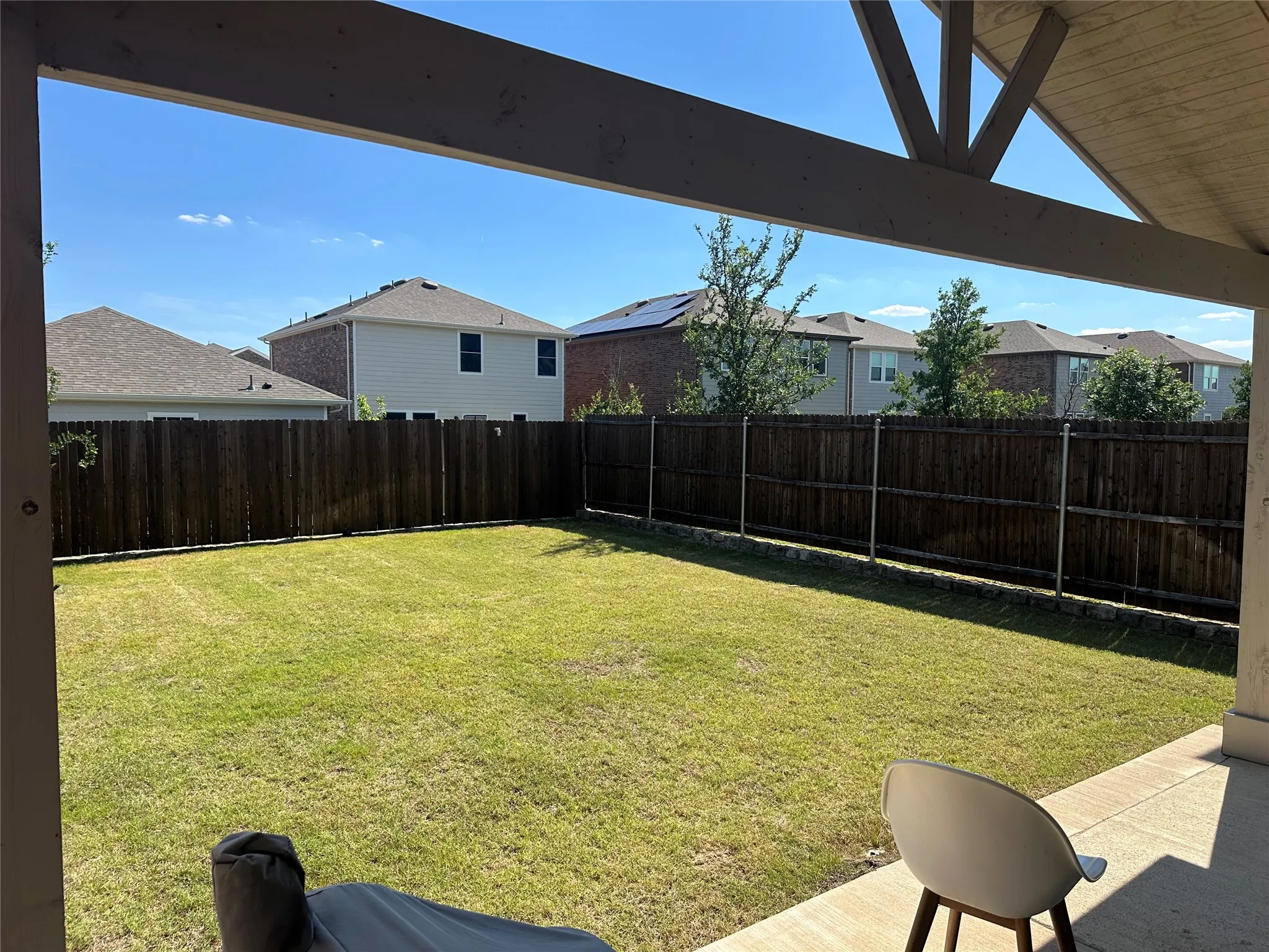 Expansive backyard featuring a manicured lawn, full privacy fencing, and a concrete patio with an overhead pergola structure