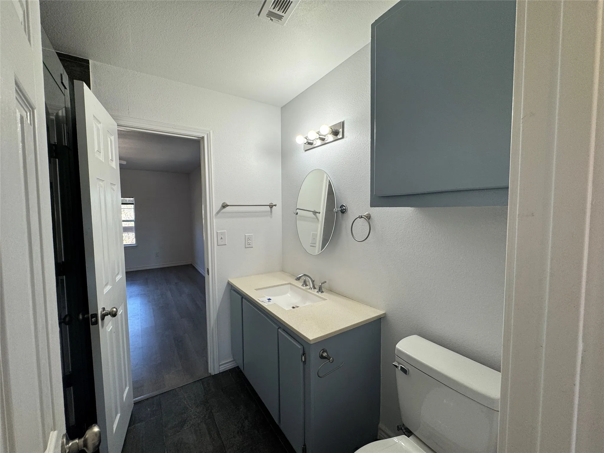 Bathroom vanity with blue cabinetry, a light-toned countertop, and an oval mirror