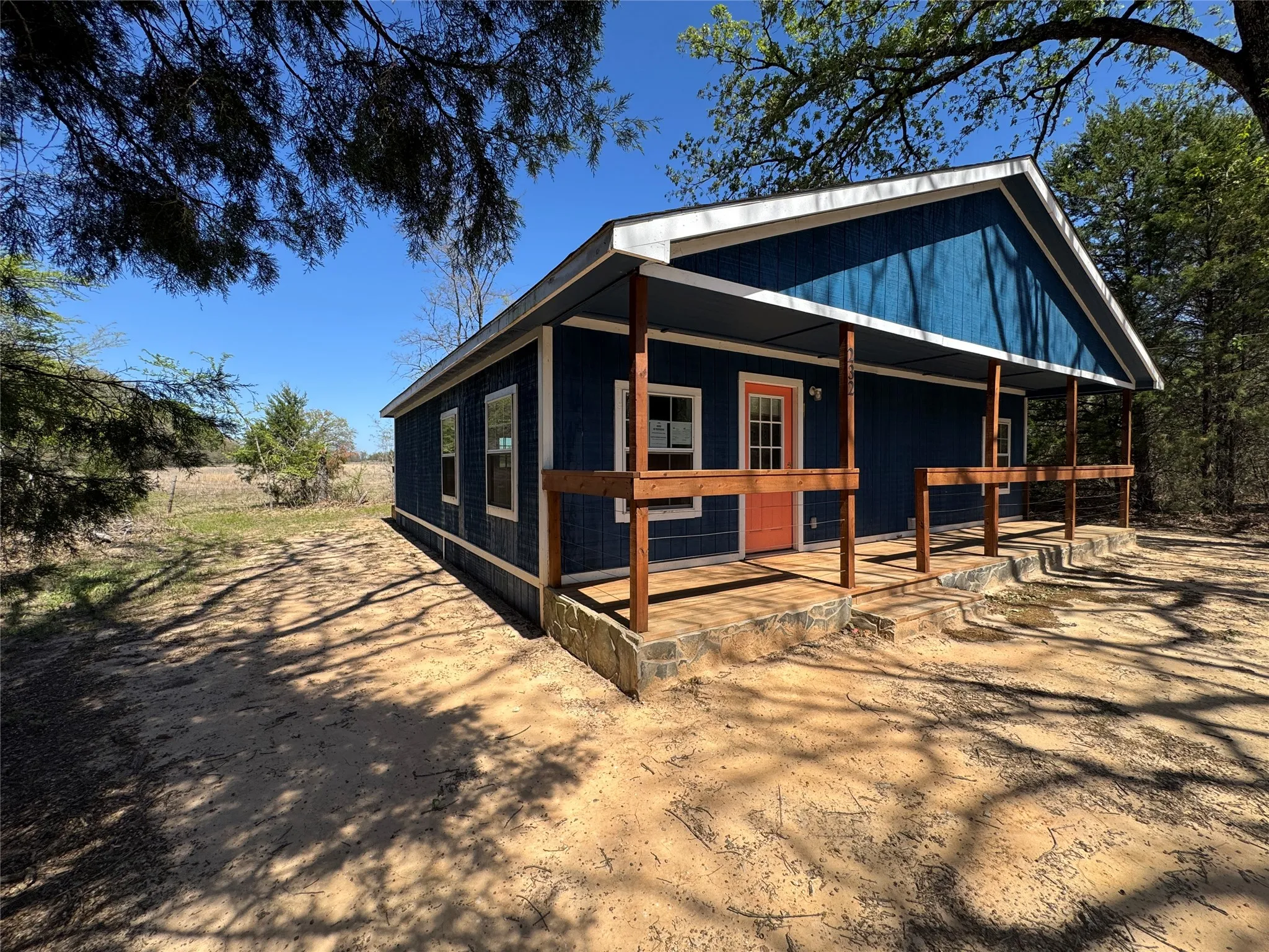 Blue exterior with a gable roofline, featuring a covered porch with wooden posts and railings