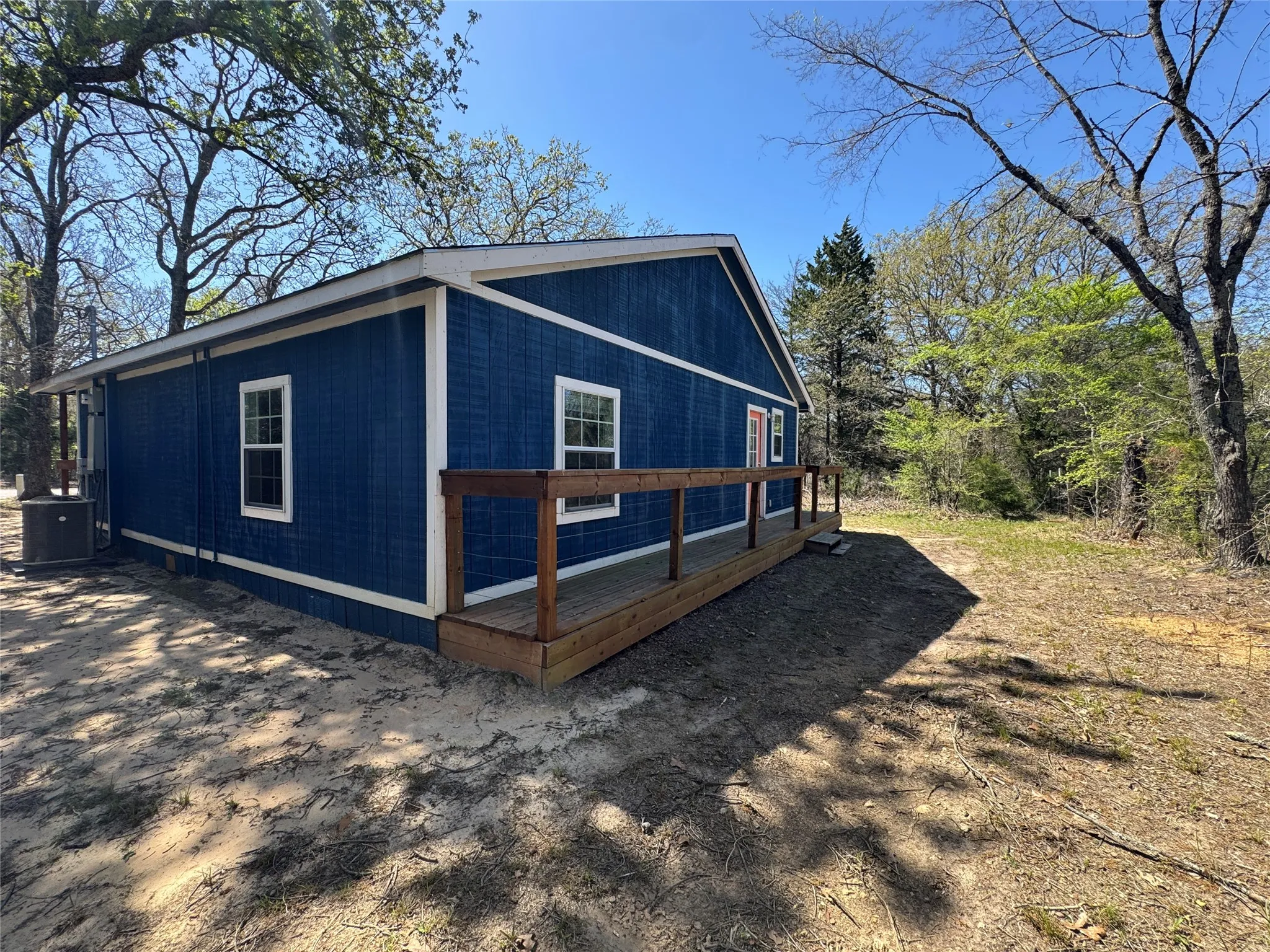 Exterior featuring rich blue siding with white trim, a wooden deck with railing, and multiple double-hung windows