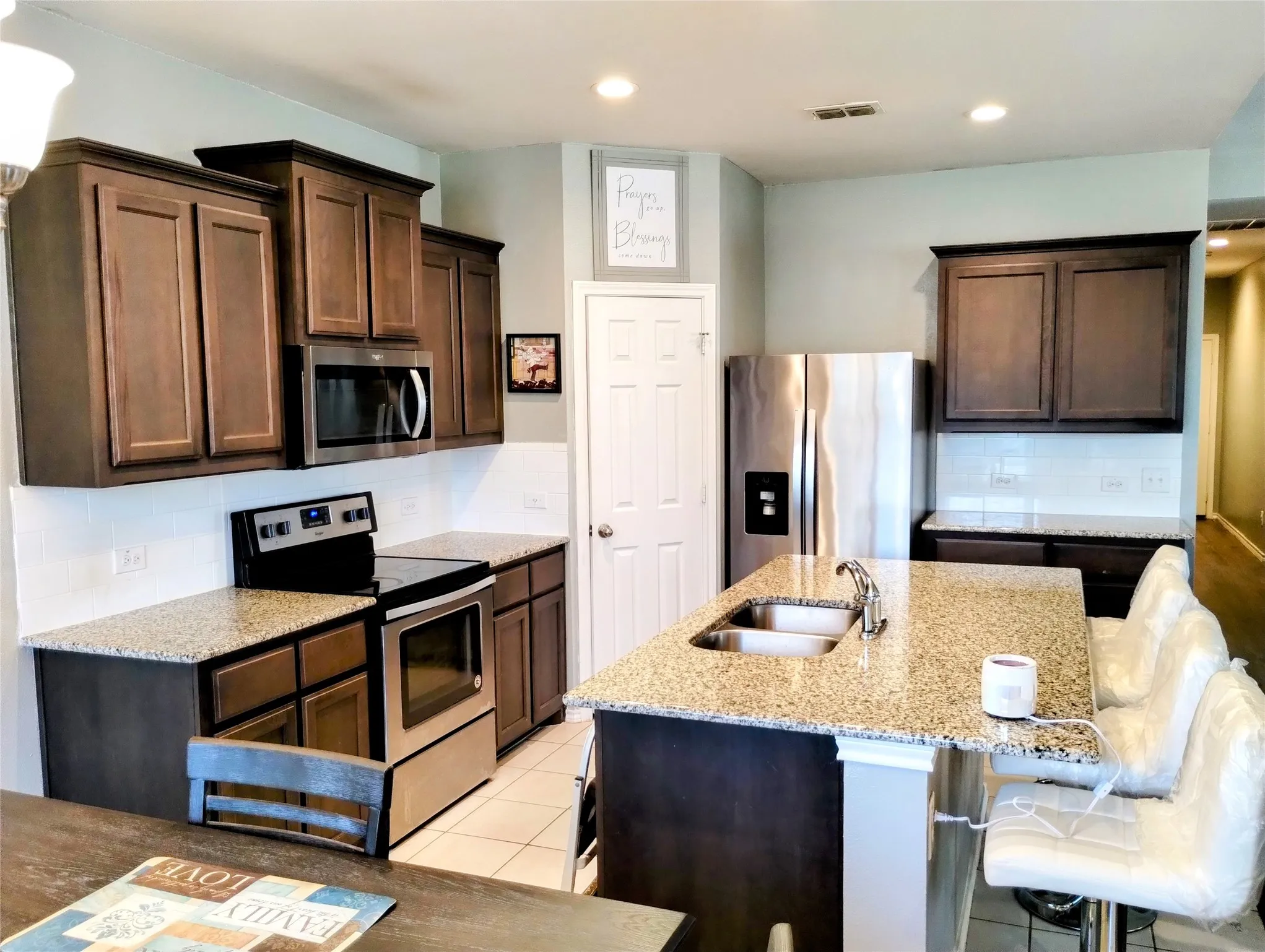 Kitchen featuring a kitchen island with sink, sink, a kitchen bar, backsplash, and appliances with stainless steel finishes