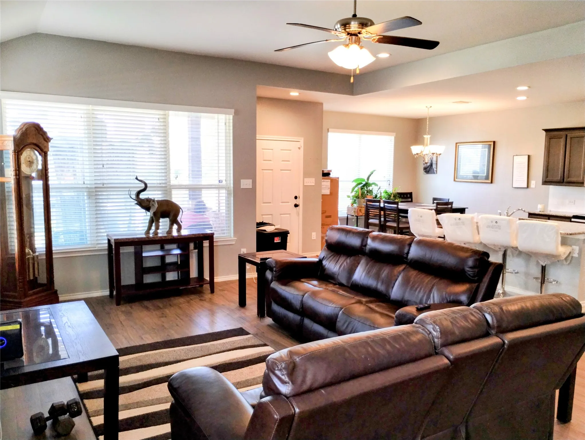 Living room with light hardwood / wood-style flooring, vaulted ceiling, and ceiling fan with notable chandelier