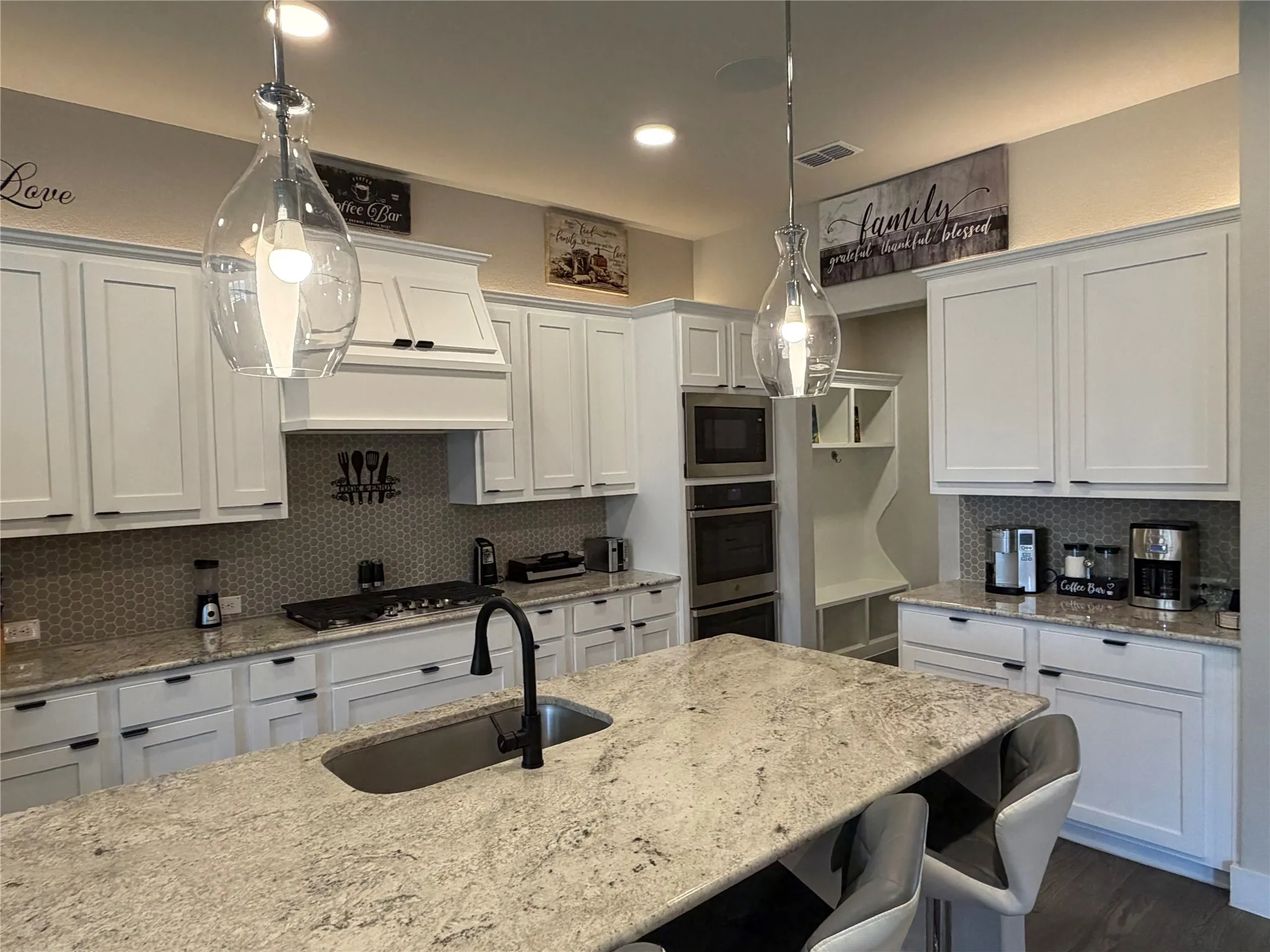 Delightful Kitchen with the Family Chef in Mind Equipped with All the Essentials. Gorgeous Granite, Large Island with Deep Single Sink and Stainless Appliances, Gas Cooktop, Microwave and Double Oven. Coffee Bar and Mud Bench by the Garage.