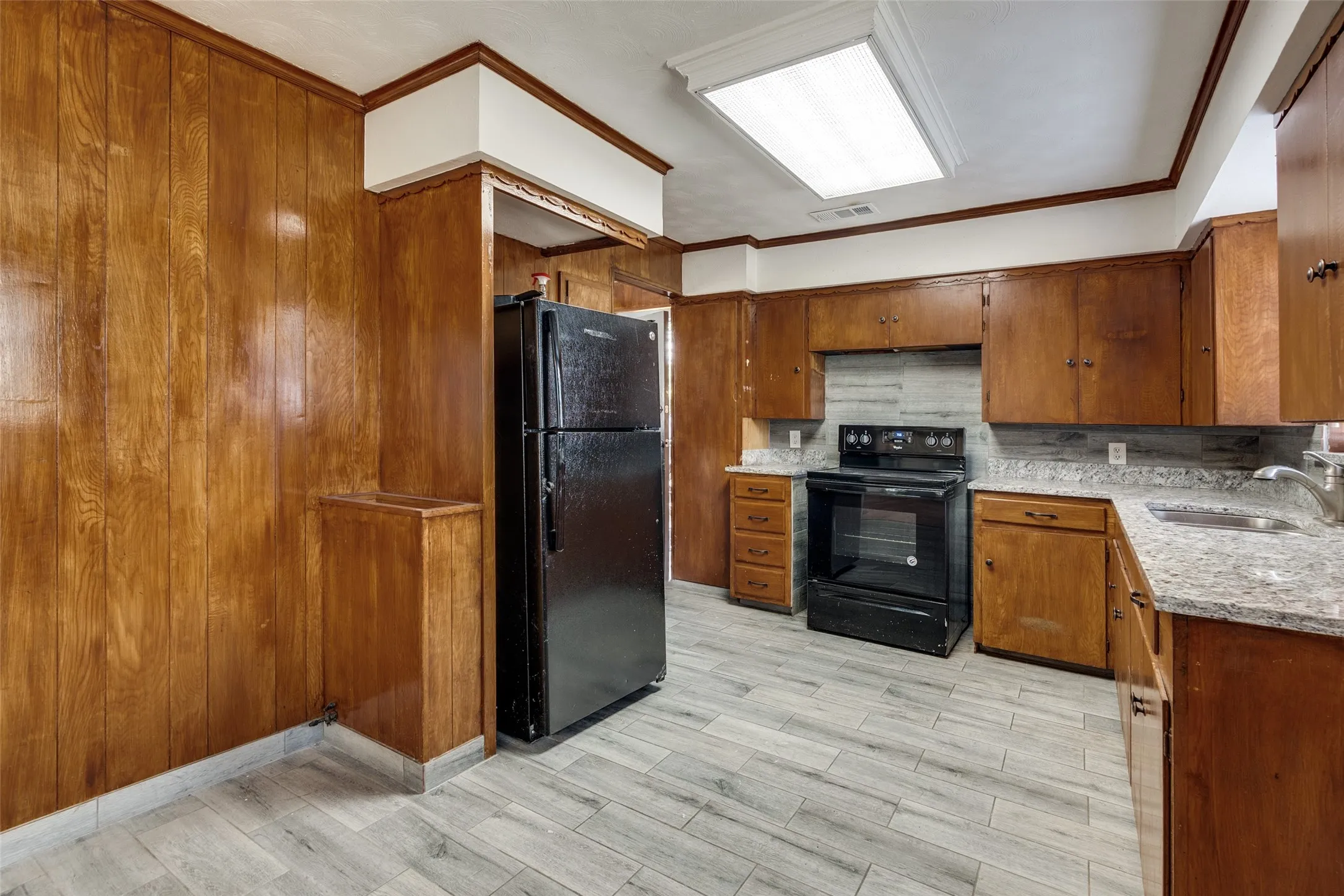 Kitchen featuring wood-finish cabinetry, light-colored countertops, a tile backsplash, and light wood-look plank flooring