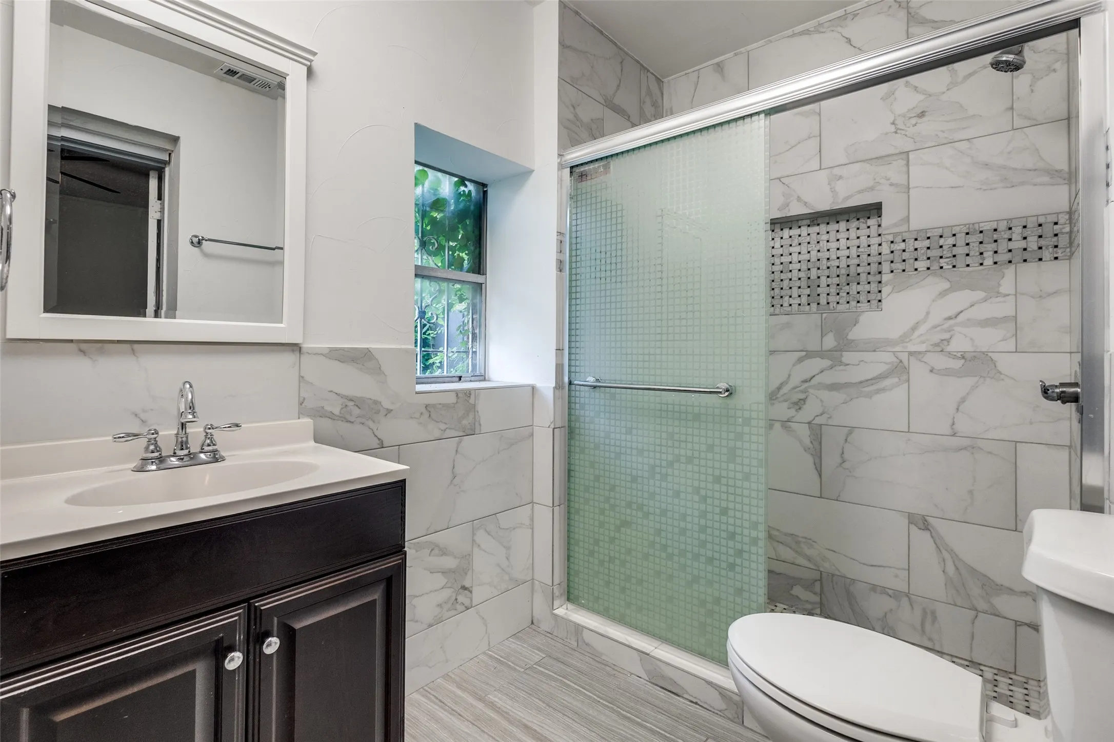 Bathroom featuring a dark wood-finish vanity with a white countertop and undermount sink, complemented by a framed mirror
