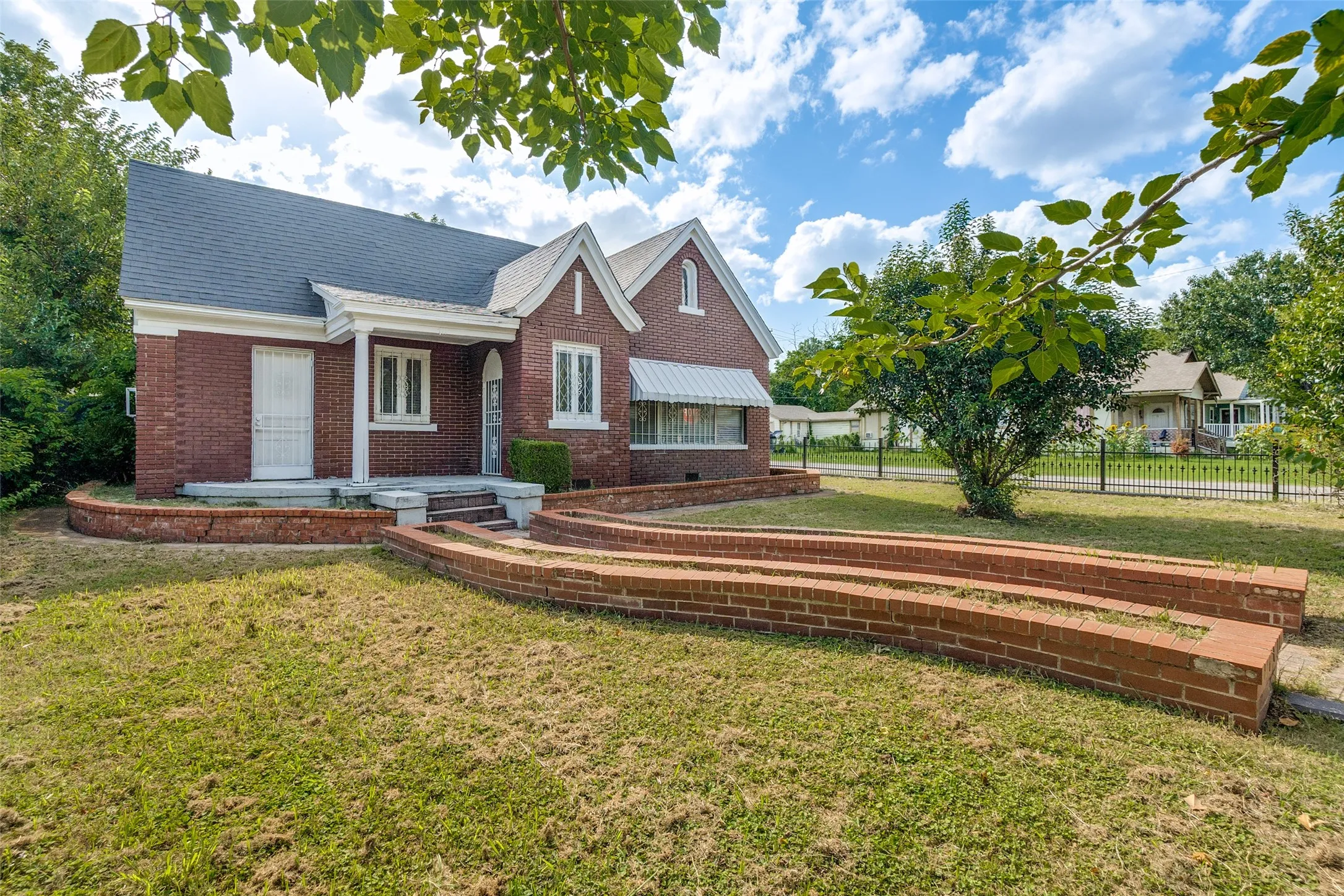 Brick exterior home with white trim and a dark shingle roof