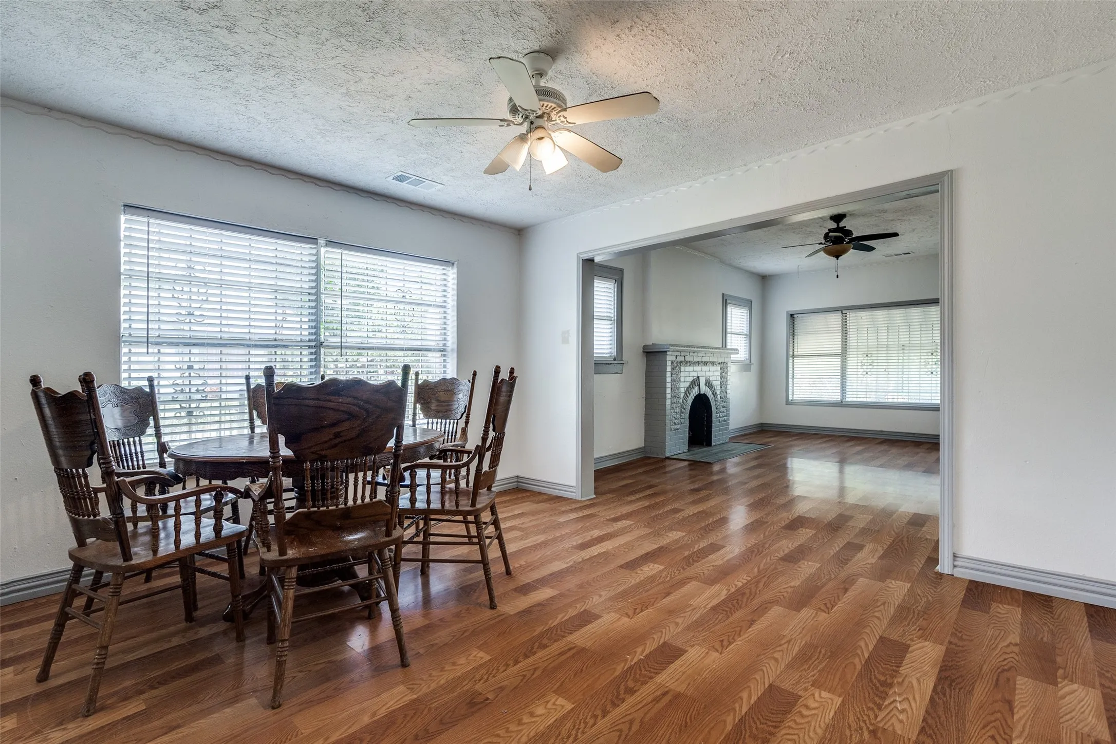 Light-filled interior featuring wood-finish flooring, a ceiling fan with light fixture, and a wide entryway