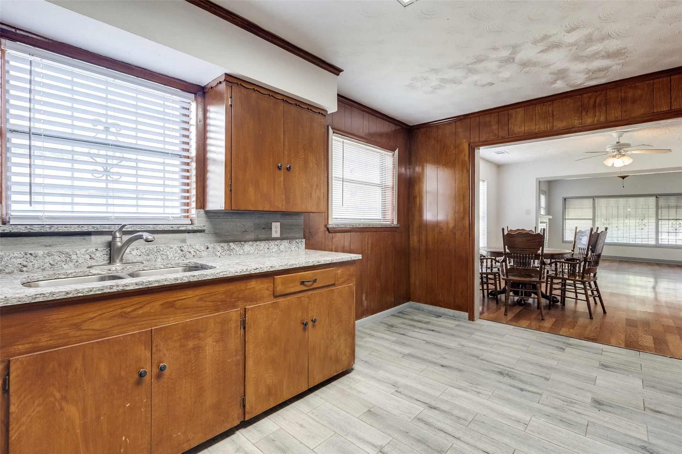 Kitchen featuring wood cabinetry, light-colored countertops, a double basin sink with a modern faucet, and light wood-finish flooring