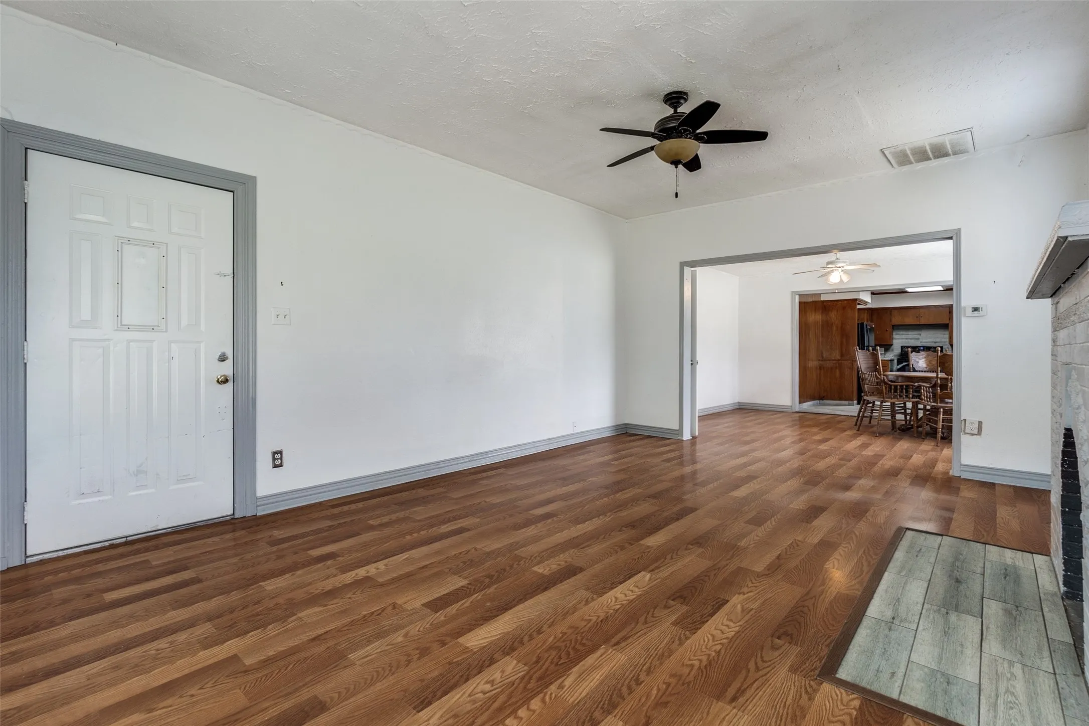 Spacious interior featuring wood-finish flooring, a ceiling fan, and a fireplace with a tiled hearth