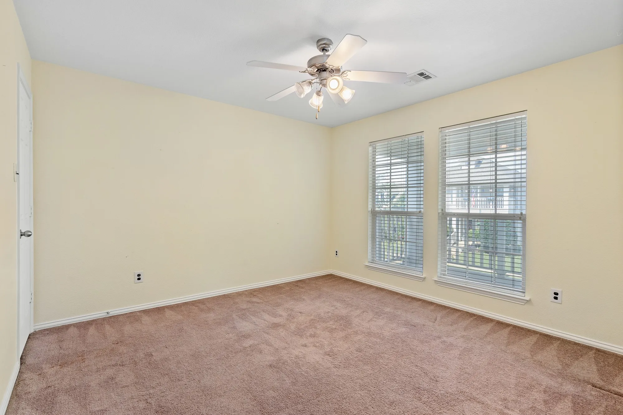 Carpeted room with two large windows featuring blinds