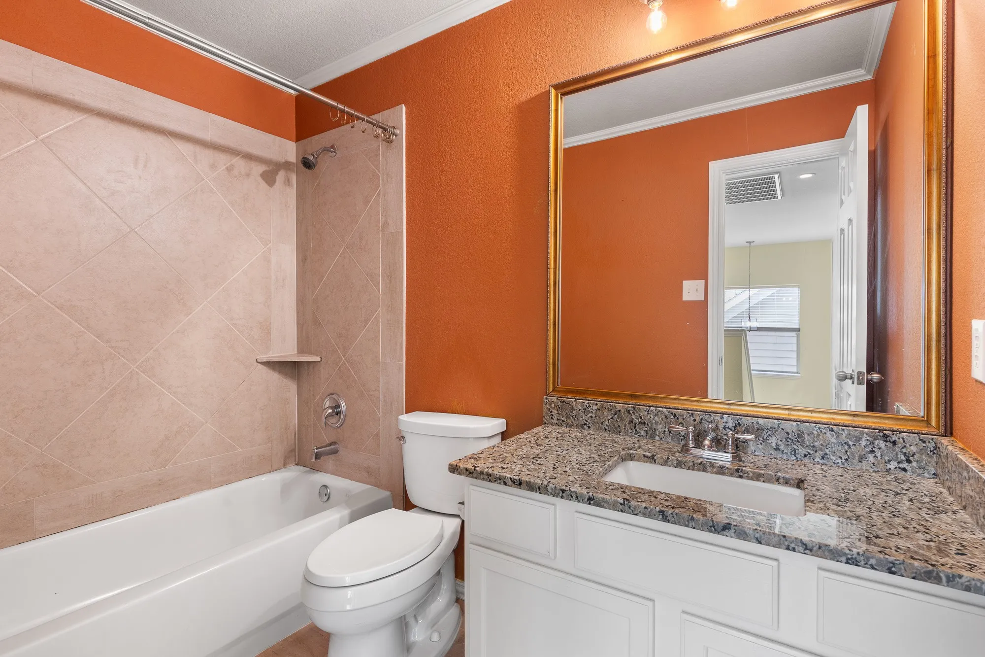 Bathroom featuring a white bathtub, ceramic tile shower surround, chrome shower fixtures, a white toilet, and a vanity with a dark granite-style countertop
