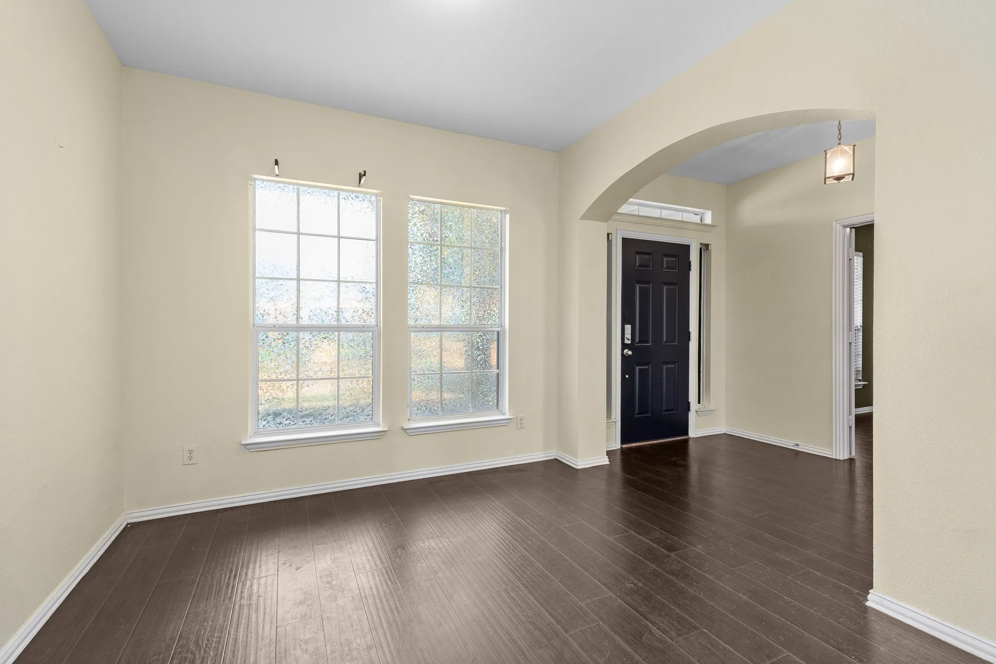 Entryway with dark wood-finish flooring, light cream wall paint, and white baseboards