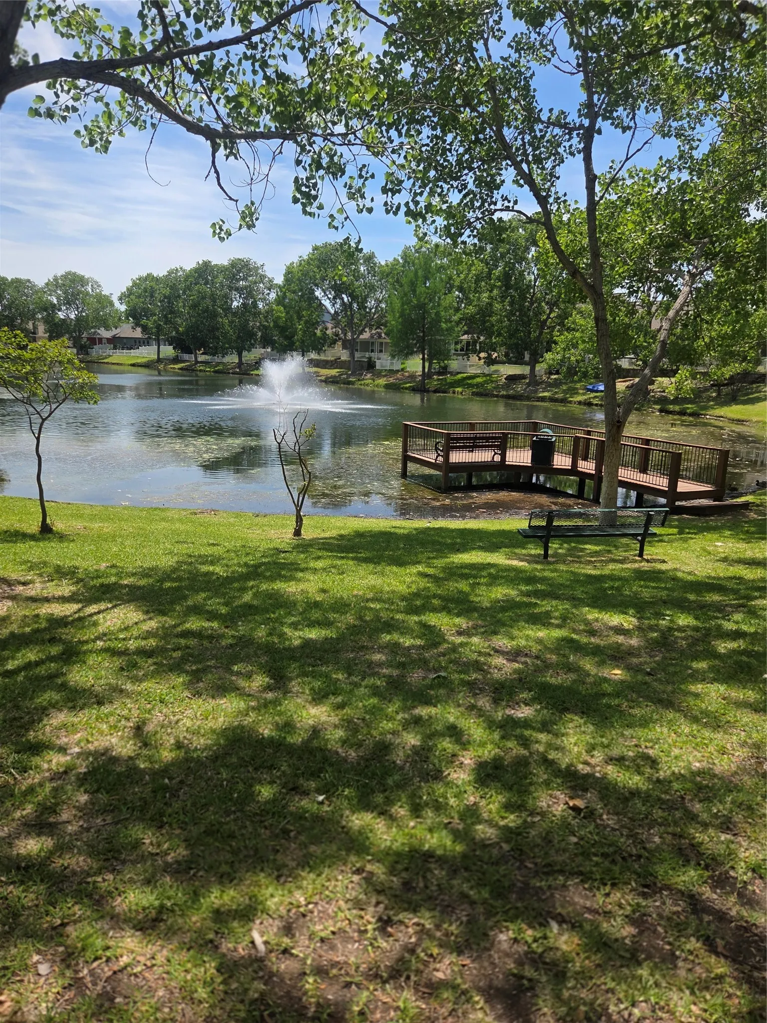 Park nearby with lake setting featuring a water fountain, wooden deck, and mature trees