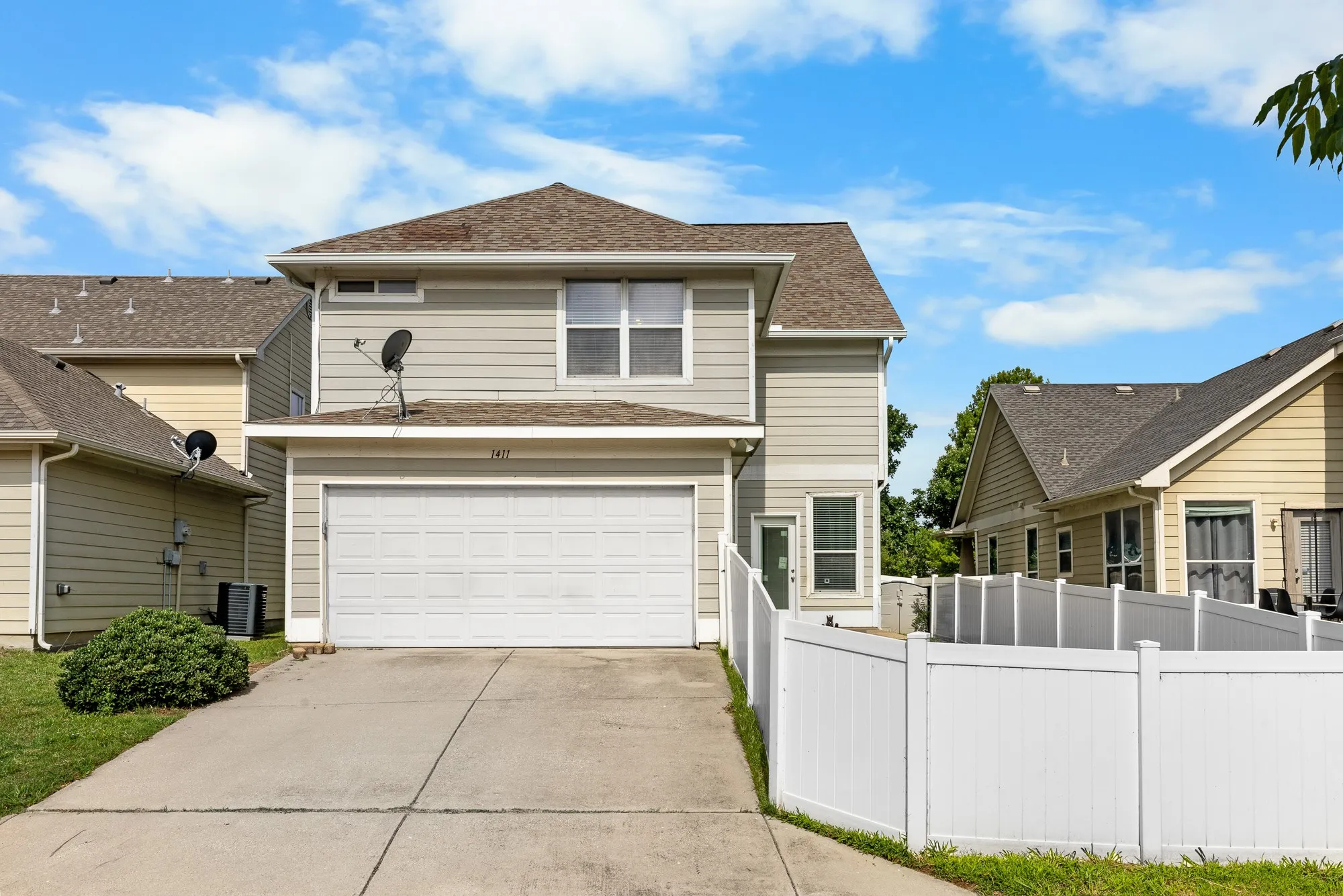Alley garage entrance with two-story residence featuring light-colored siding, a two-car garage, and a concrete driveway