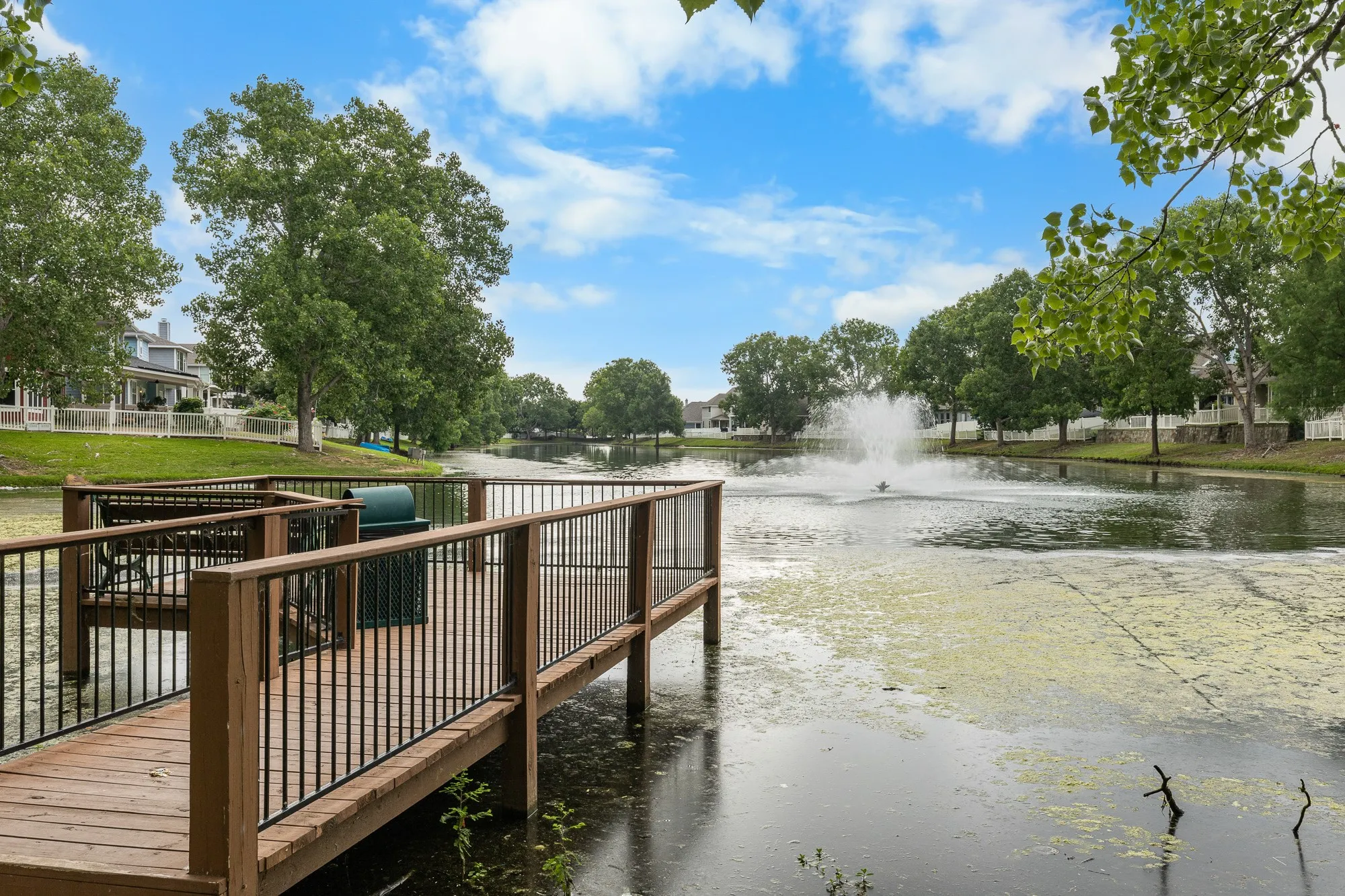 Nearby Park with Dock, wood decking and black metal railings extending over a body of water