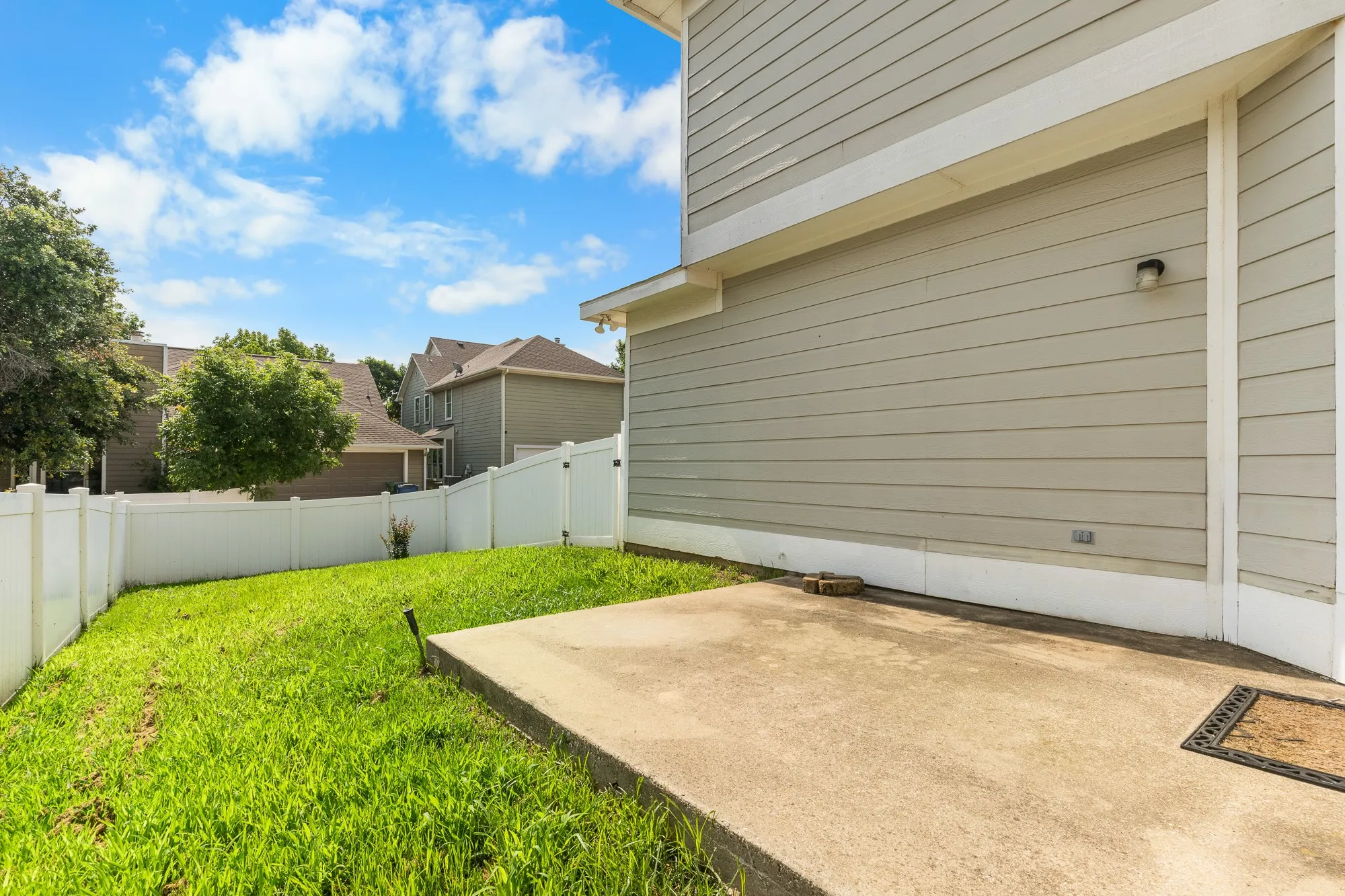 Backyard featuring a concrete patio, perimeter fencing, and a grassy area