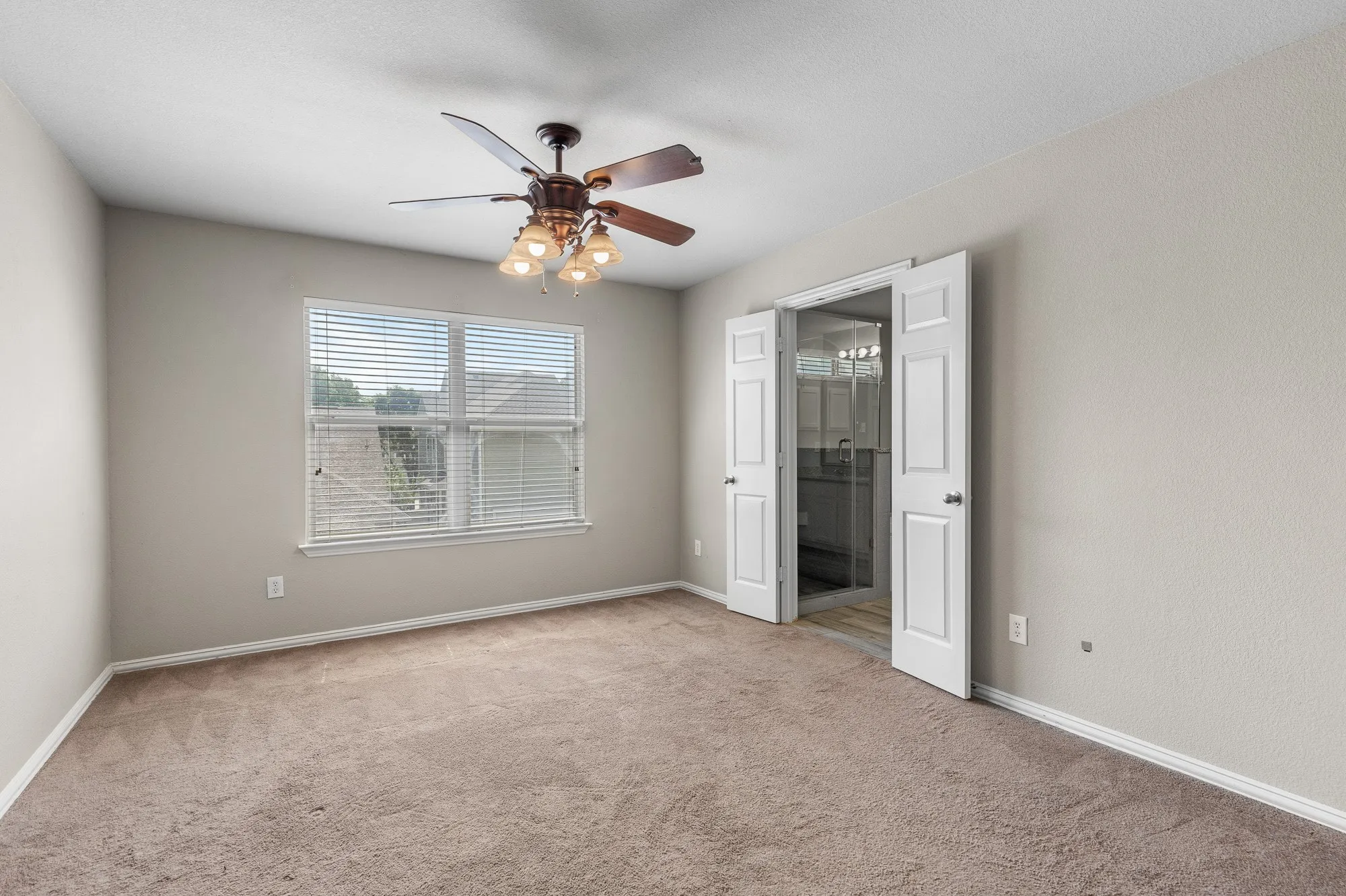 Carpeted interior room with a ceiling fan light fixture, two-panel interior doors, and a double window with blinds