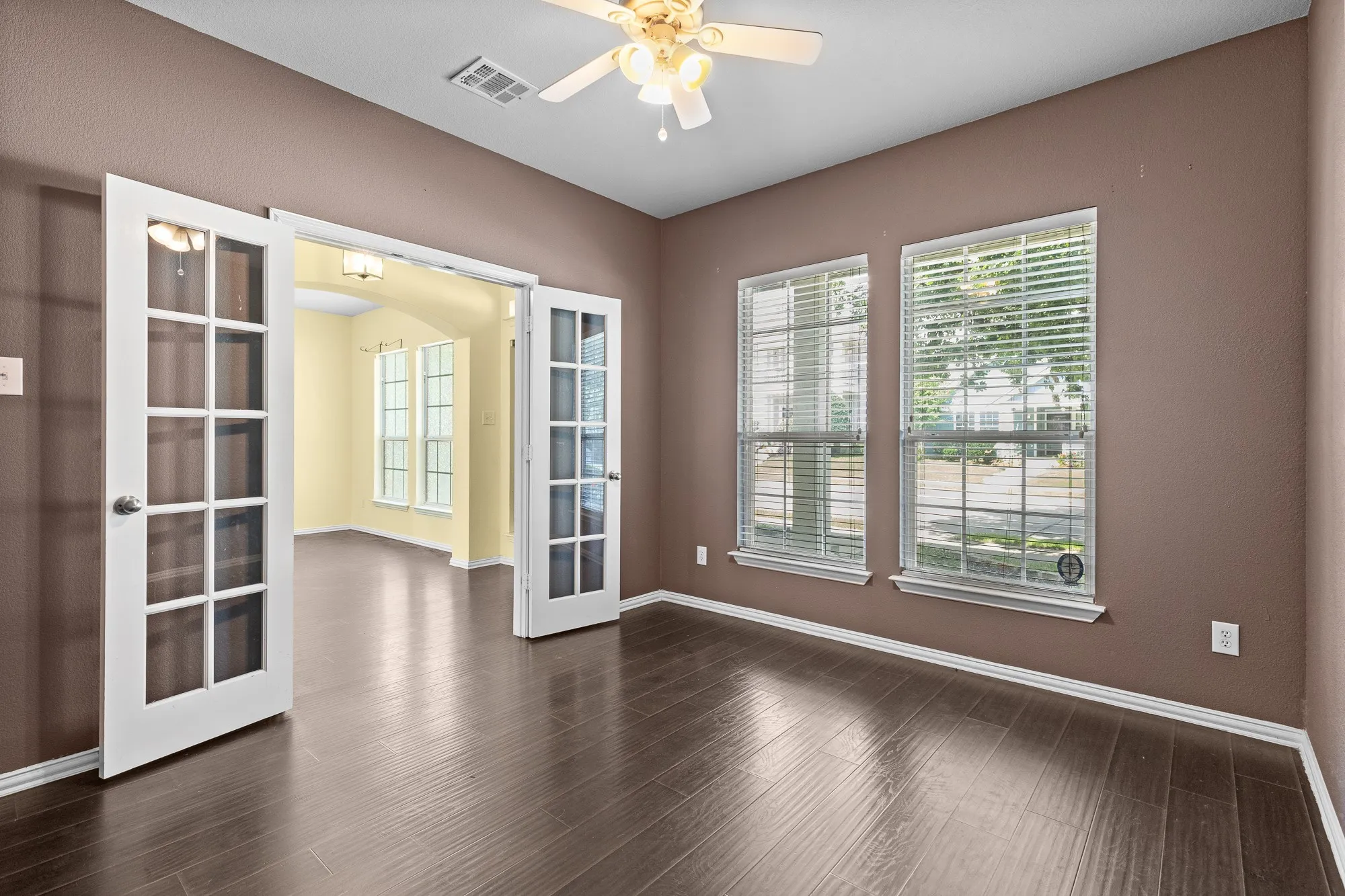 Spacious room  or office featuring wood-finish flooring, white trim, and two large windows