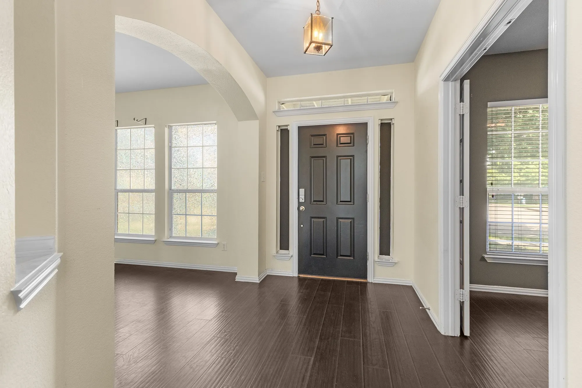 Entryway featuring dark wood-finish flooring, a paneled front door with sidelight windows, and an overhead lantern-style light fixture