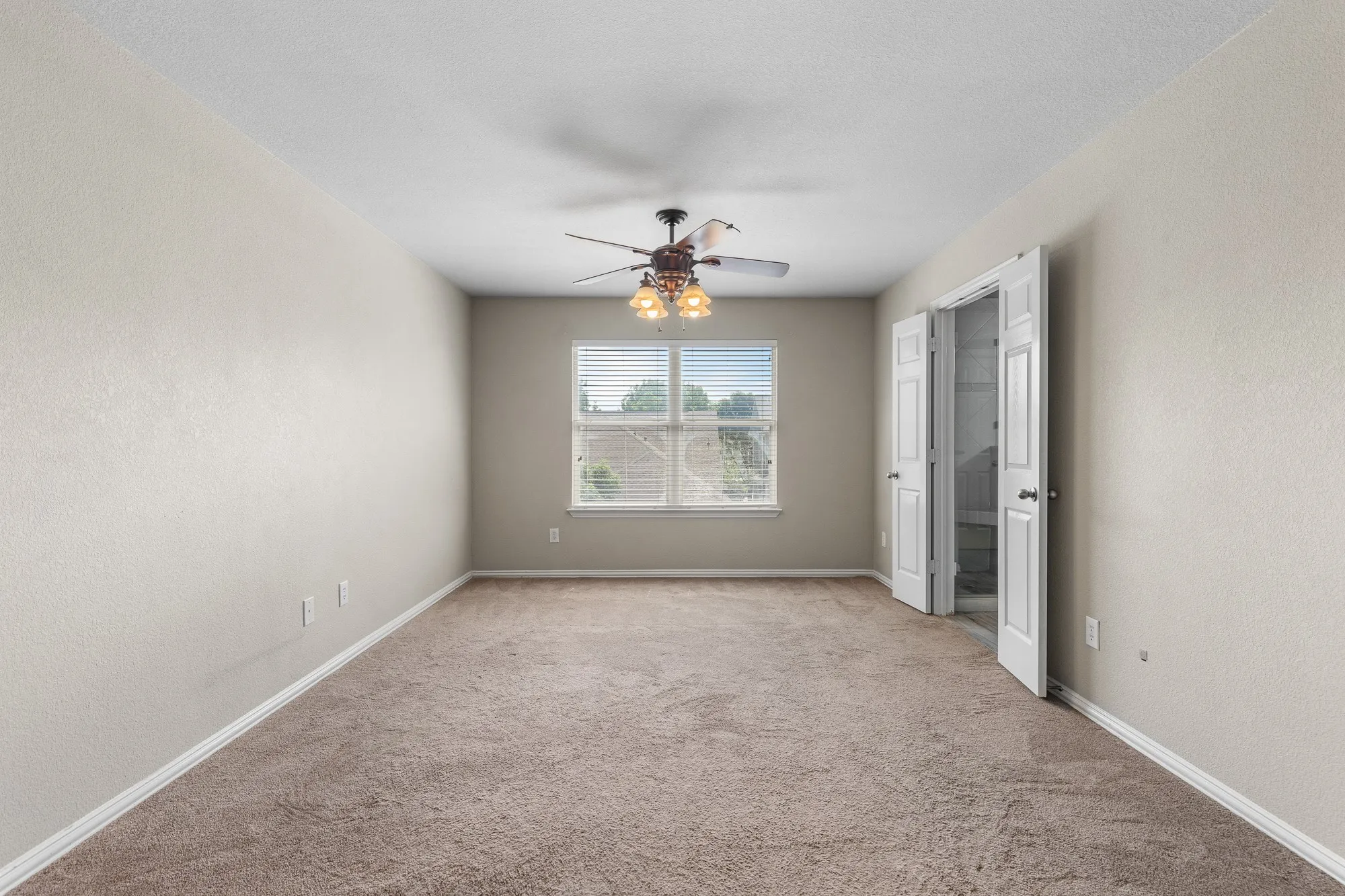 Carpeted room featuring a ceiling fan with integrated lighting, a window with horizontal blinds, and a double-door entryway