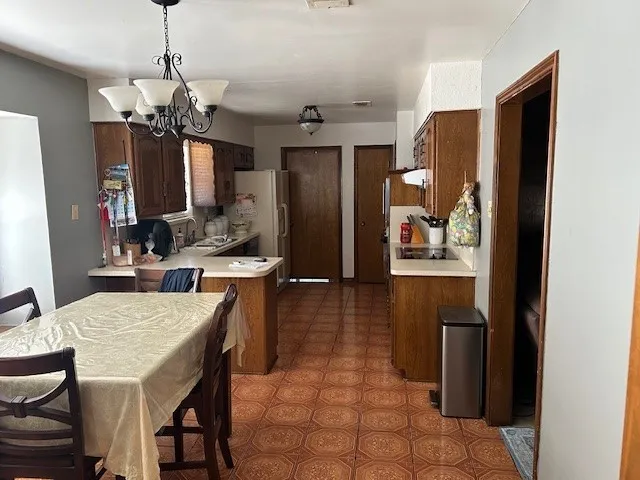 Kitchen featuring wood cabinetry, white countertops, tile flooring, and a dining area with an overhead chandelier