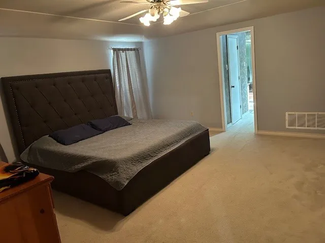 Carpeted bedroom featuring light gray walls, white trim, and a ceiling fan with integrated lighting
