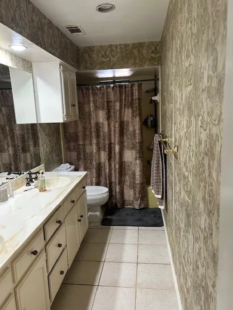 Bathroom featuring a dual-sink vanity with a light-toned countertop, white cabinetry with dark hardware, and a wall-mounted mirror