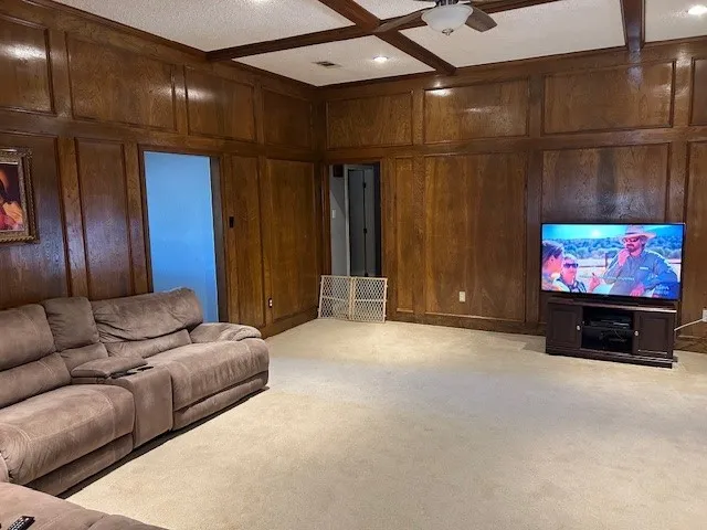 Carpeted room featuring extensive wood paneling, recessed lighting, and a ceiling fan