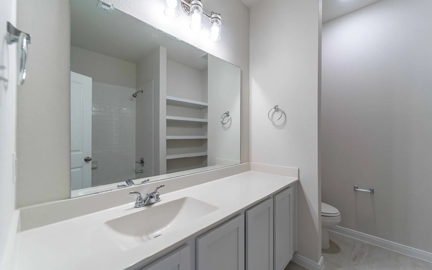Bathroom vanity featuring a single integrated sink, light-toned countertop, and shaker-style cabinetry