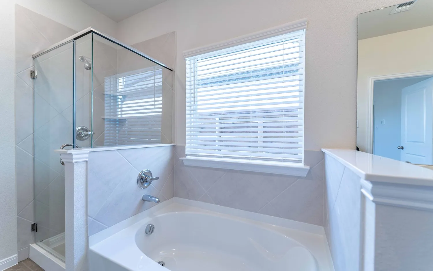 Bathroom featuring a built-in soaking tub and a glass-enclosed shower with tiled walls