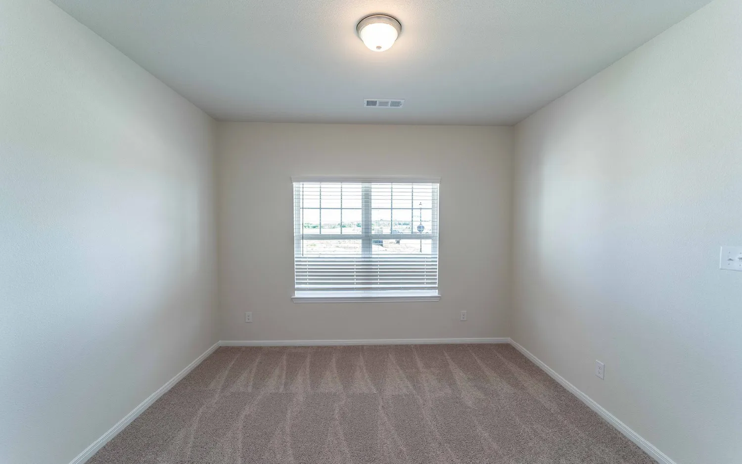 Room featuring neutral-toned carpet, a single window with blinds, and a flush-mount ceiling light fixture