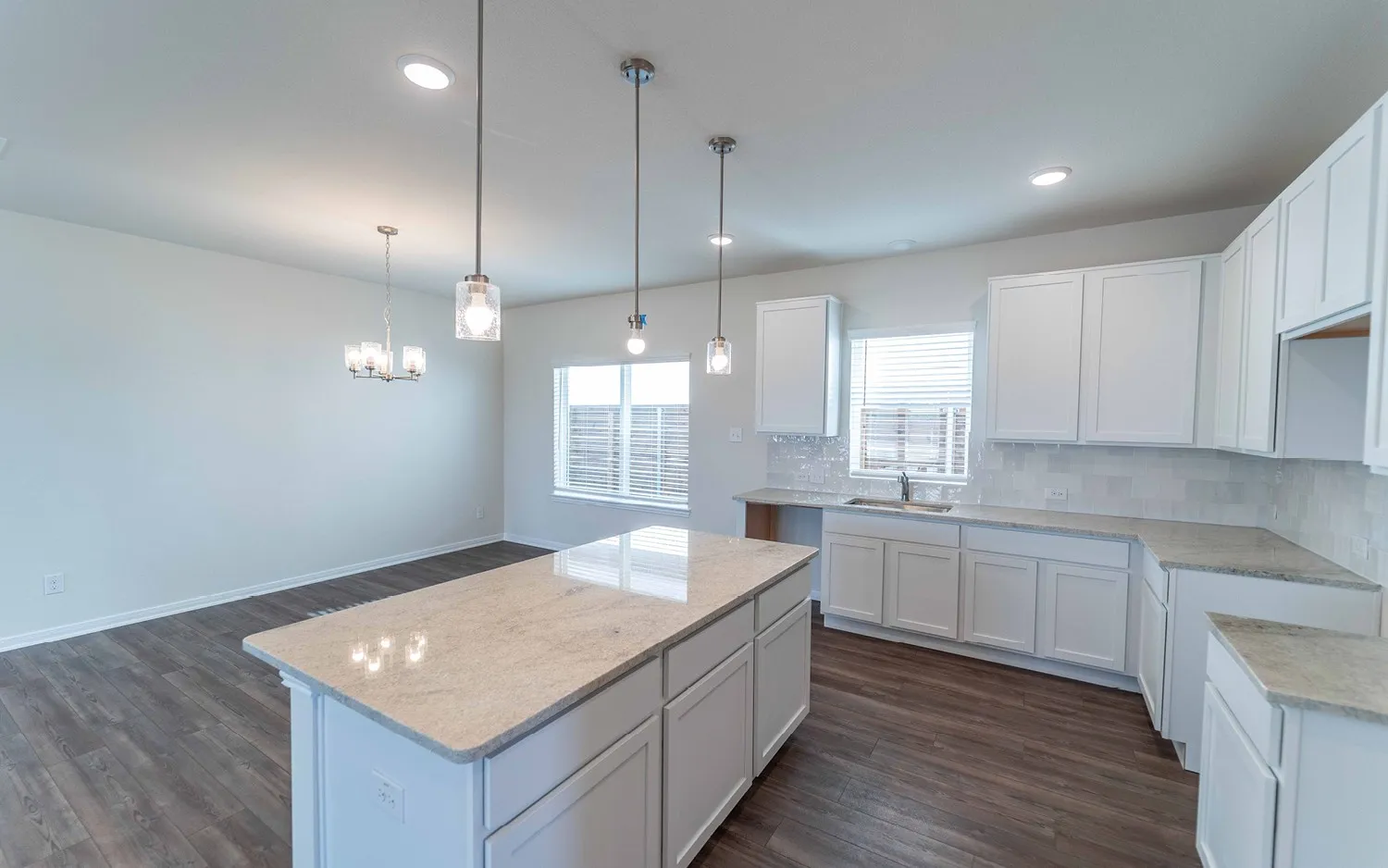 Kitchen island with a light-toned countertop, white cabinetry, wood-finish flooring, recessed lighting, and pendant fixtures