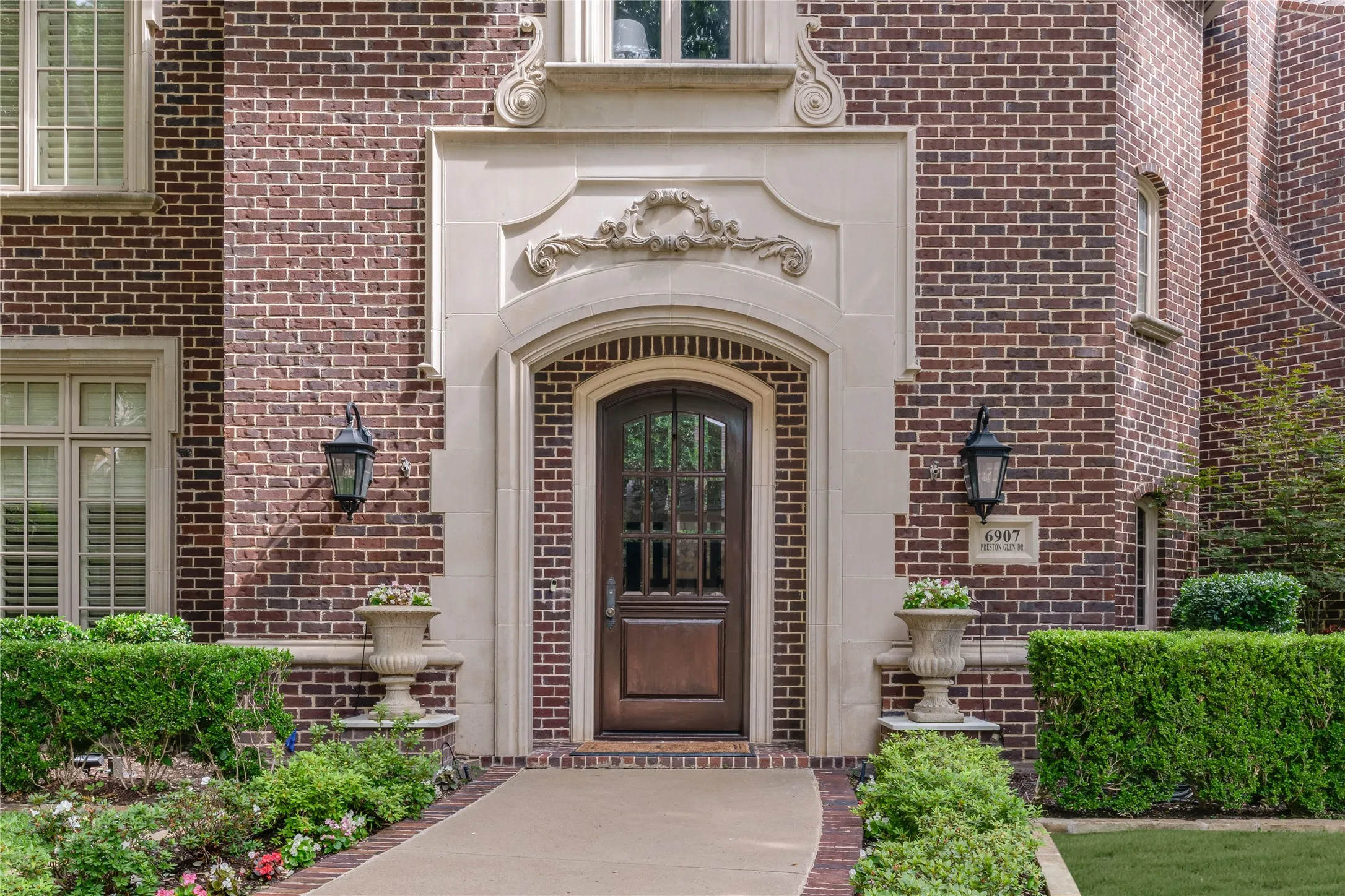 Stately entry surrounded by pretty flowering lush landscaping