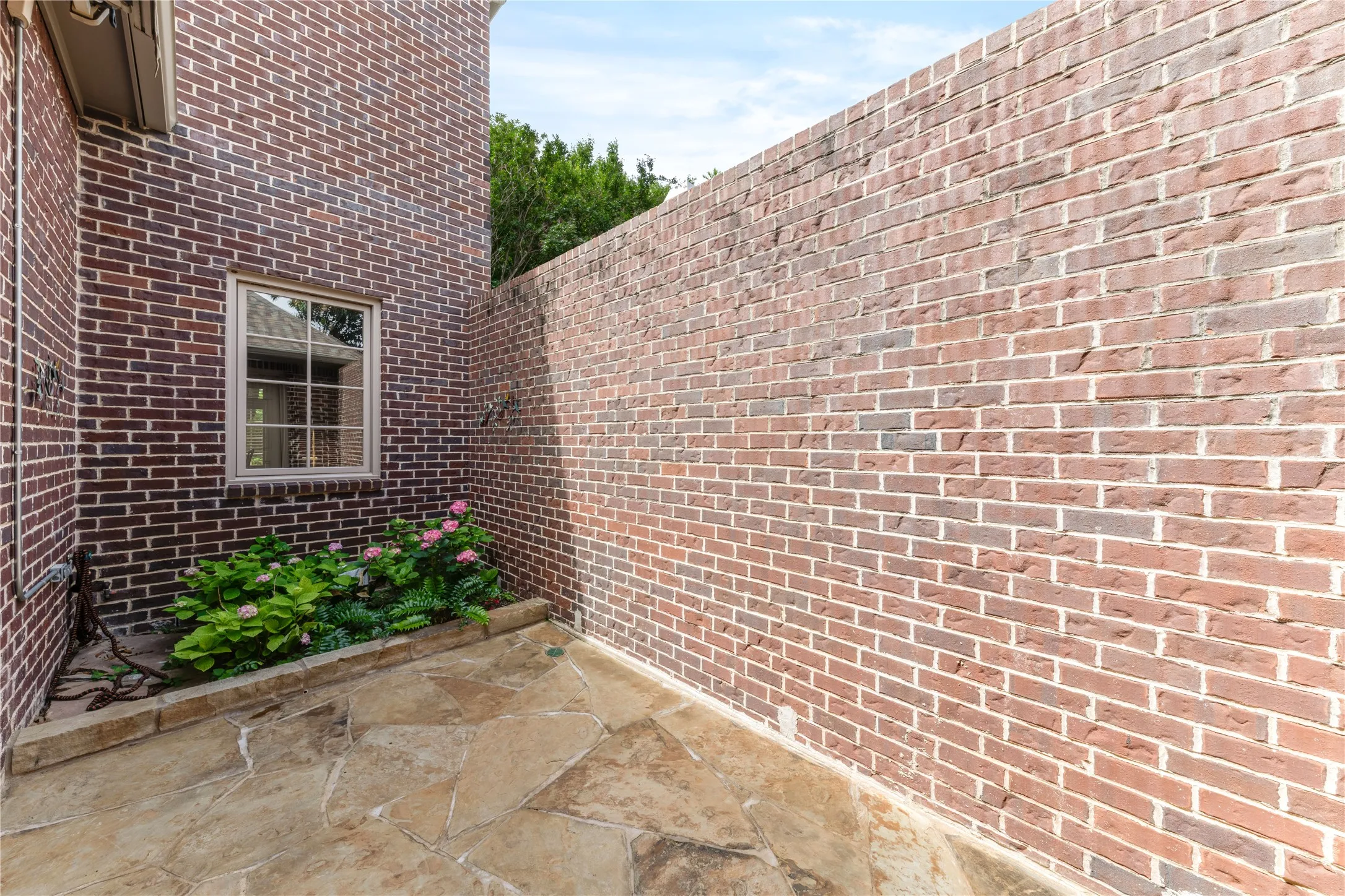 Charming courtyard featuring flagstone flooring and a raised planting bed with pretty hydrangeas