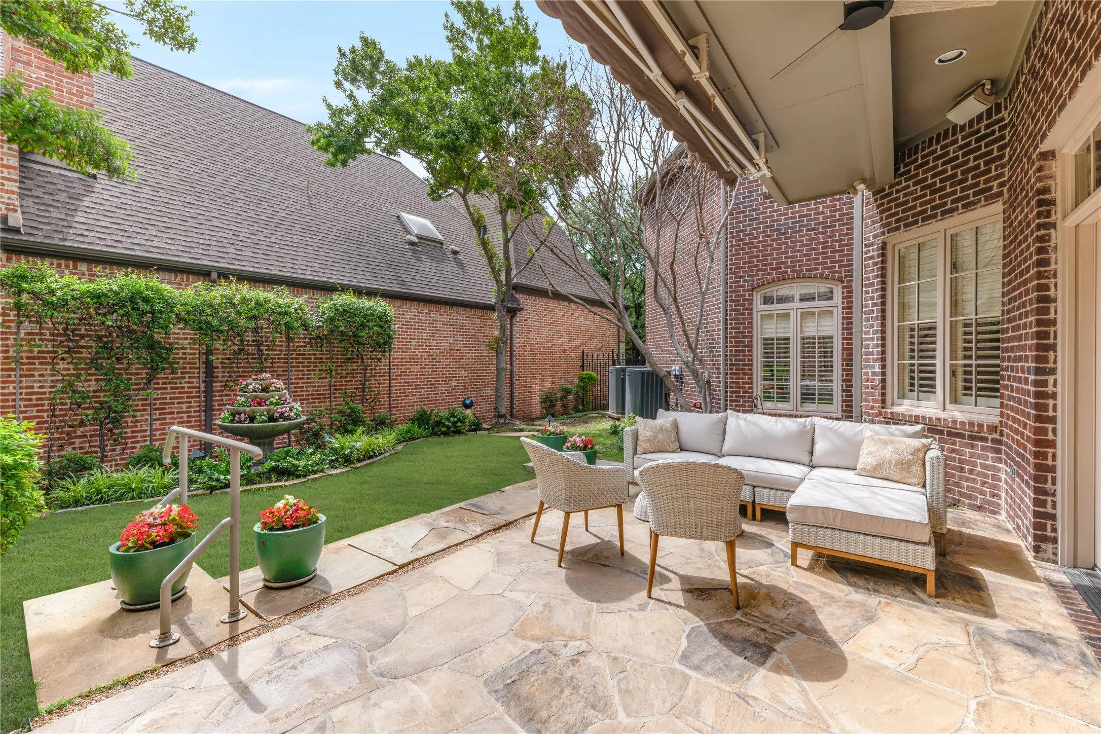 Expansive flagstone patio with a covered section, brick exterior, and pretty views from primary and living areas.