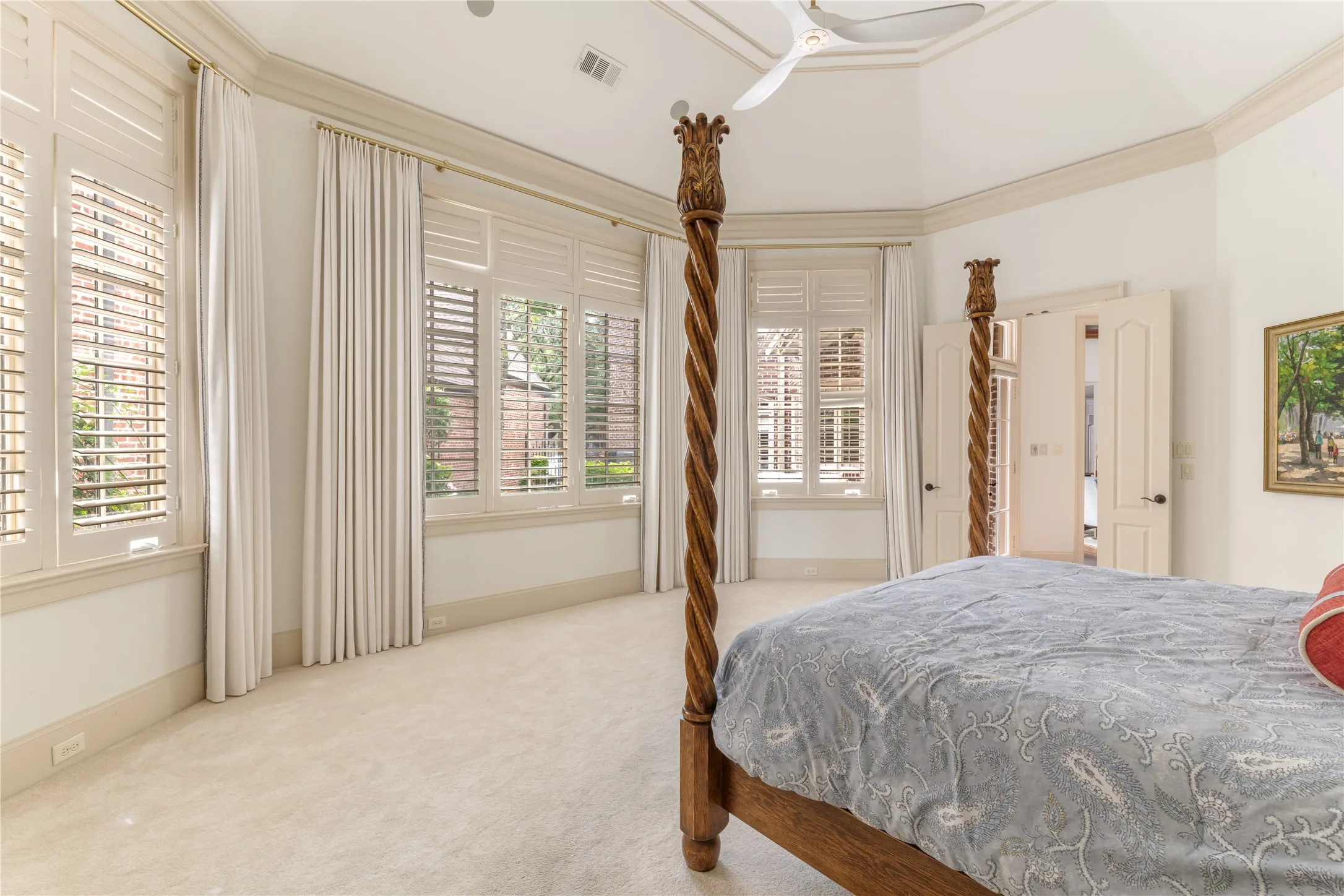 Spacious room featuring vaulted ceilings, light-toned carpeting, and multiple windows with plantation shutters and drapes