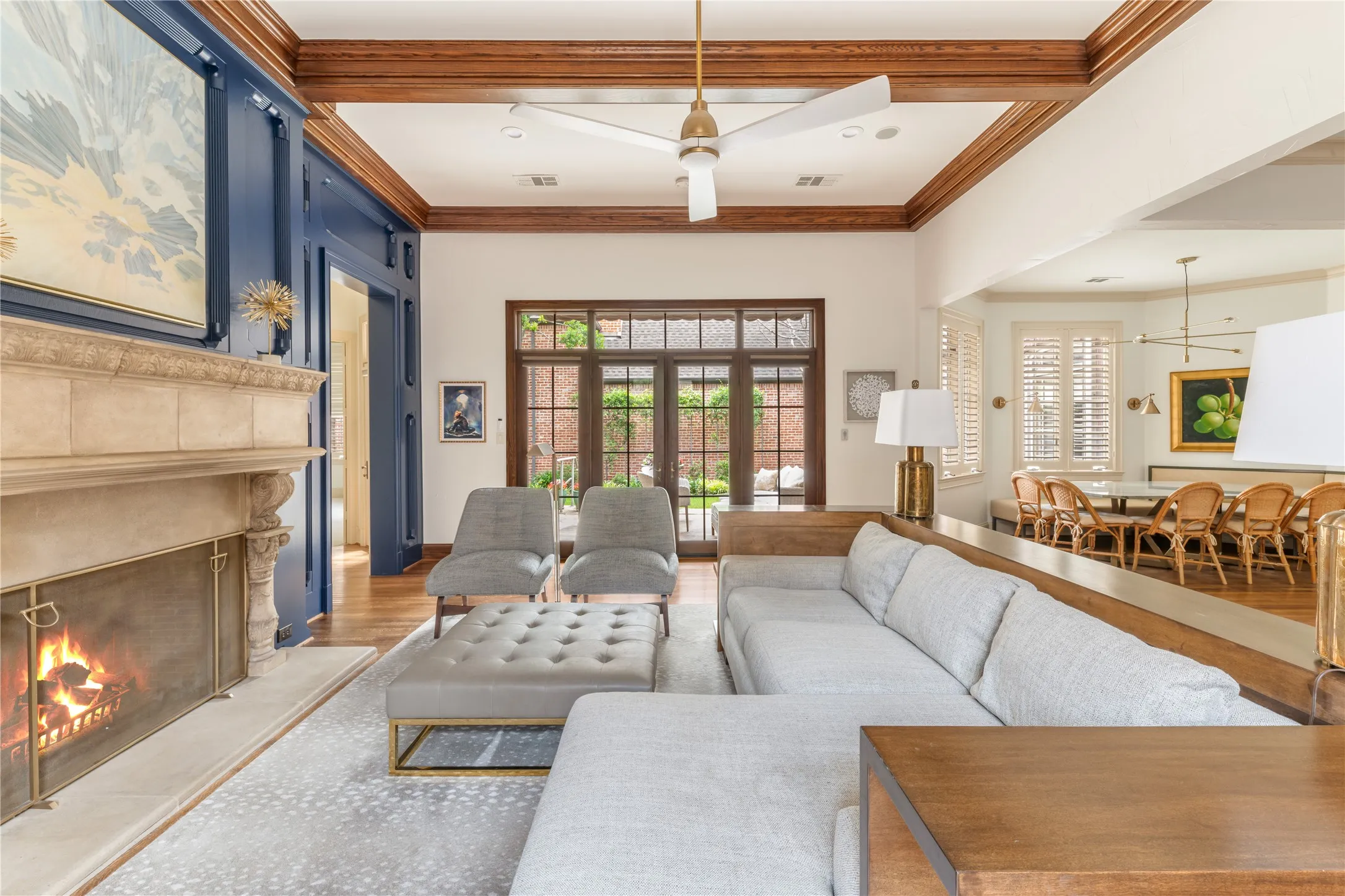 Living area featuring a stone fireplace with hearth, dark wood-paneled accent wall, wood-finish flooring, and exposed wood beam ceiling