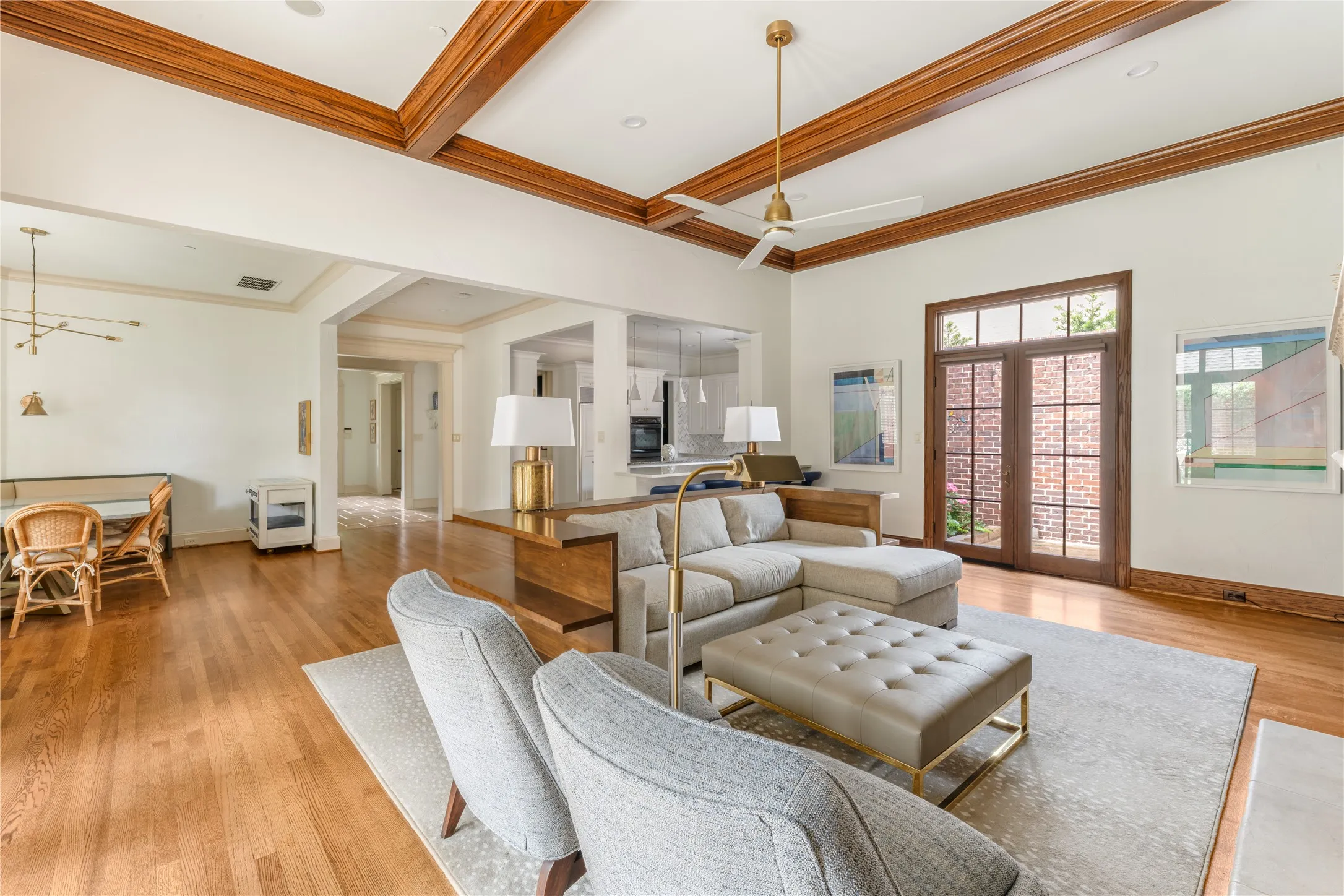 Spacious living area featuring wood-finish flooring, coffered ceilings with exposed wood beams, and a modern ceiling fan