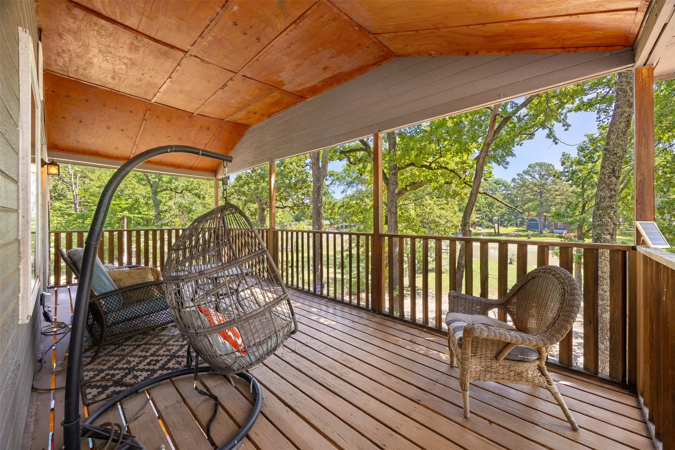 Expansive covered porch featuring wood-finish flooring, a wood-paneled ceiling, and a wooden railing