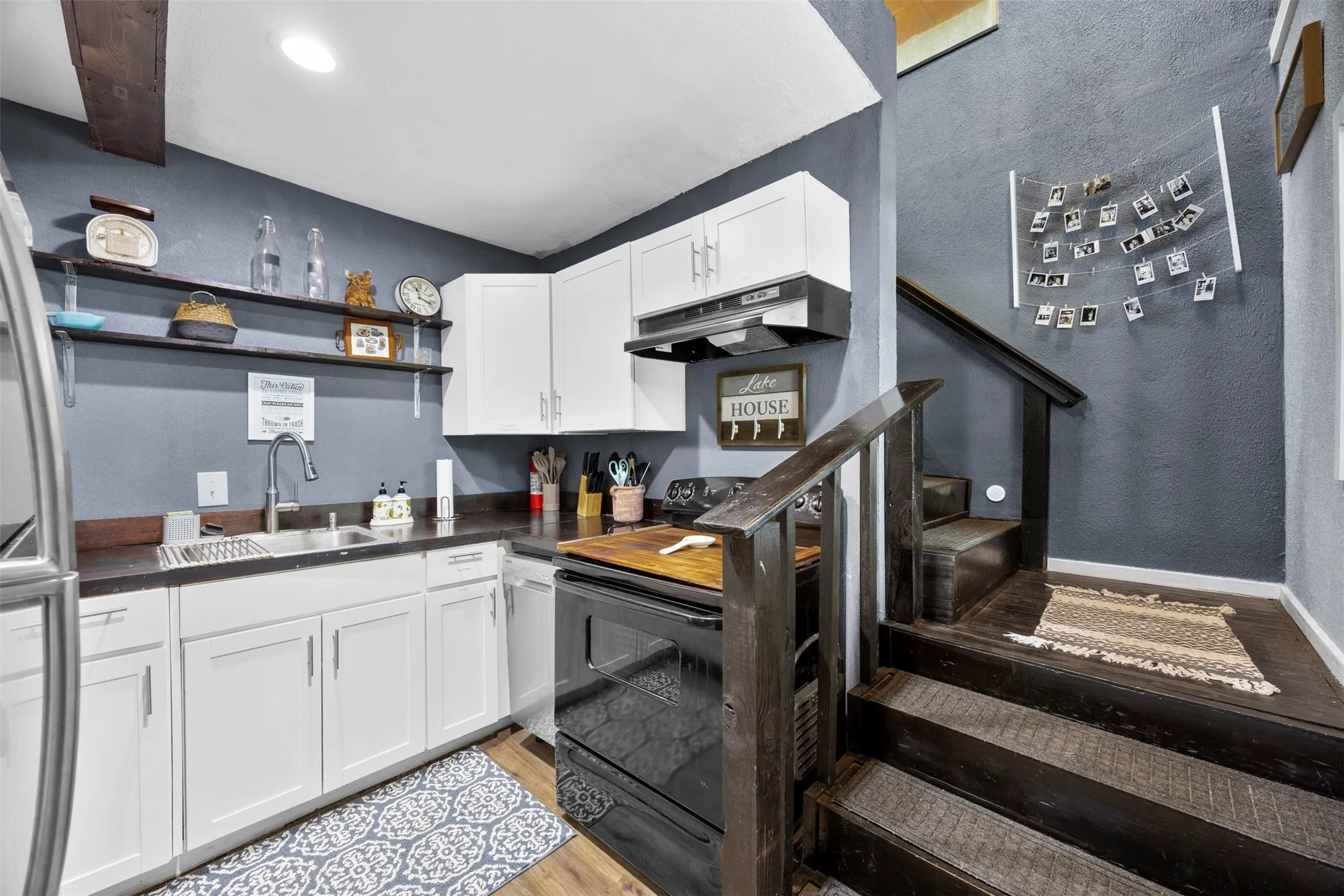 Kitchen area featuring white cabinetry, dark countertops, and a stainless steel sink