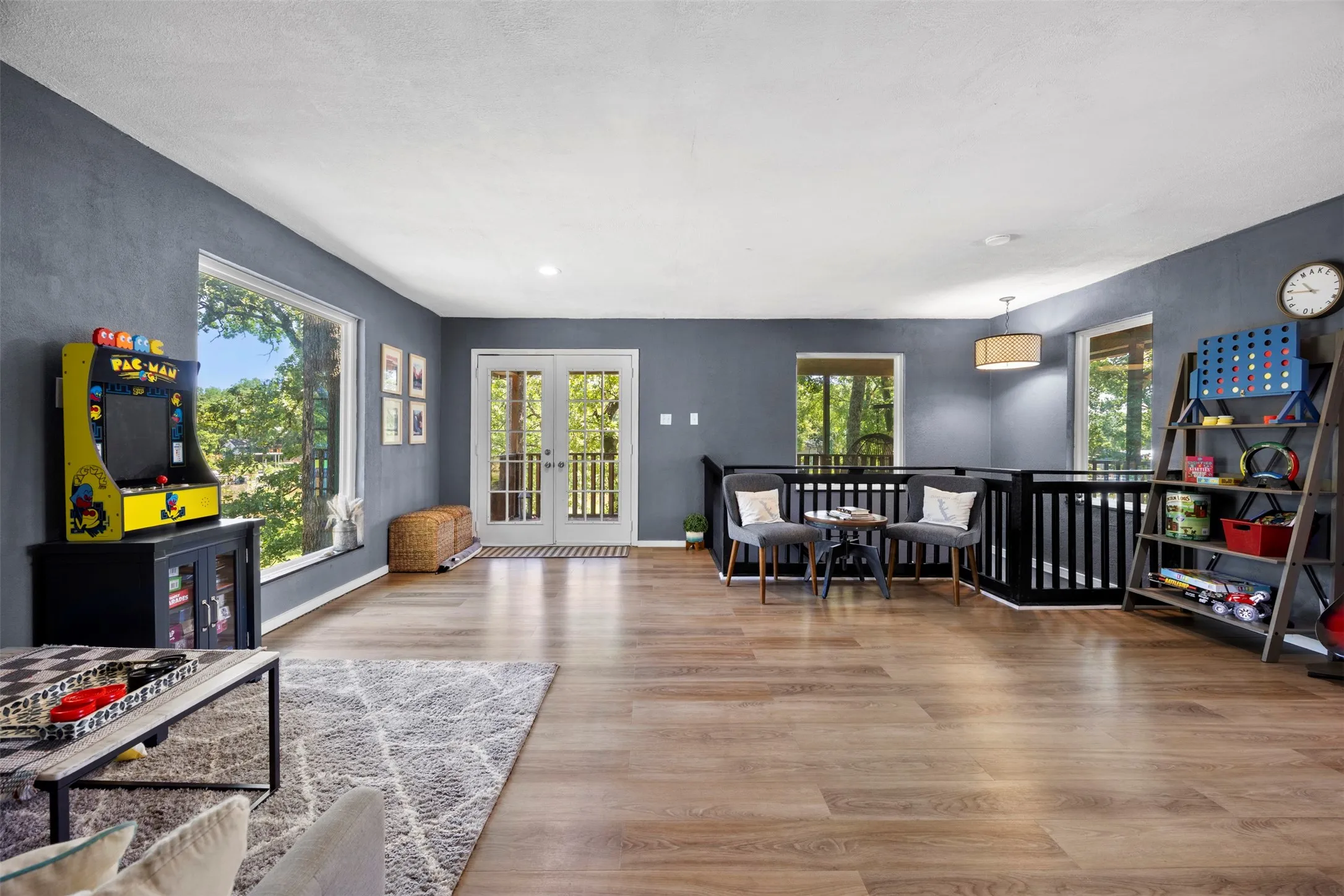 Spacious room featuring wood-finish flooring, dark accent walls, and a white ceiling