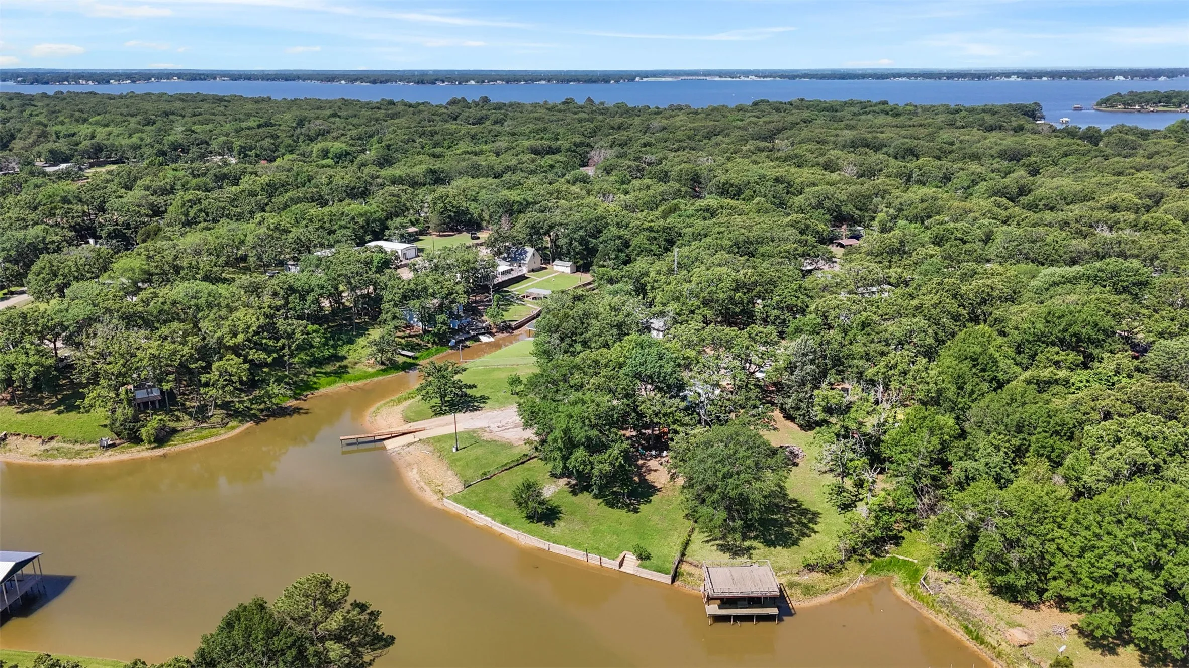 Waterfront property featuring a private dock, expansive green spaces, mature tree coverage, and direct water access