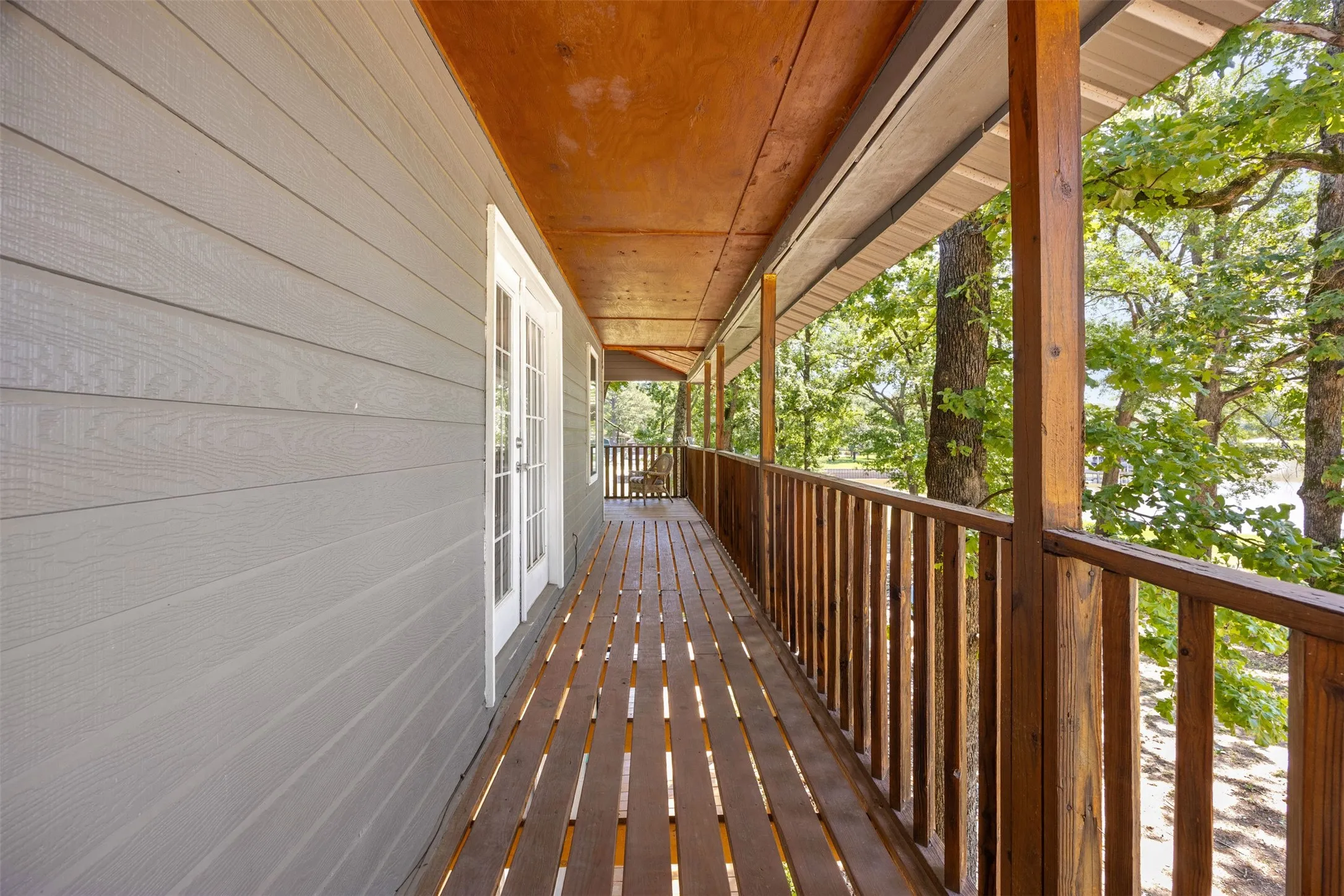 Expansive wooden deck featuring horizontal plank flooring, a matching wooden railing, and supportive wooden posts