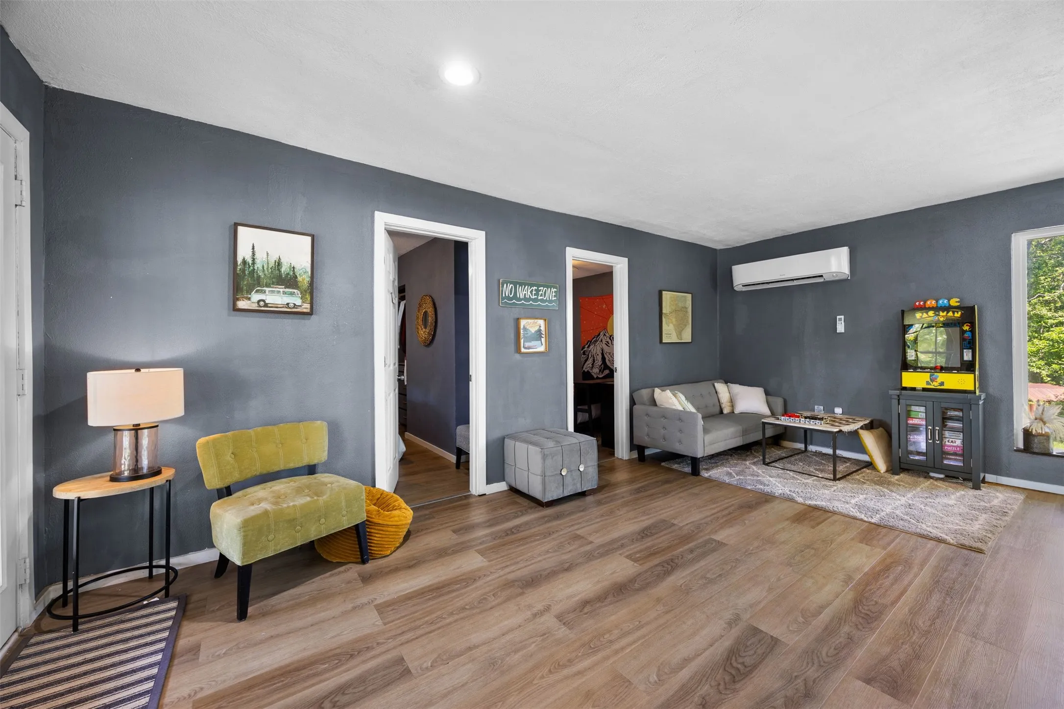 Spacious interior room featuring wood-finish flooring, dark accent walls, and white trim